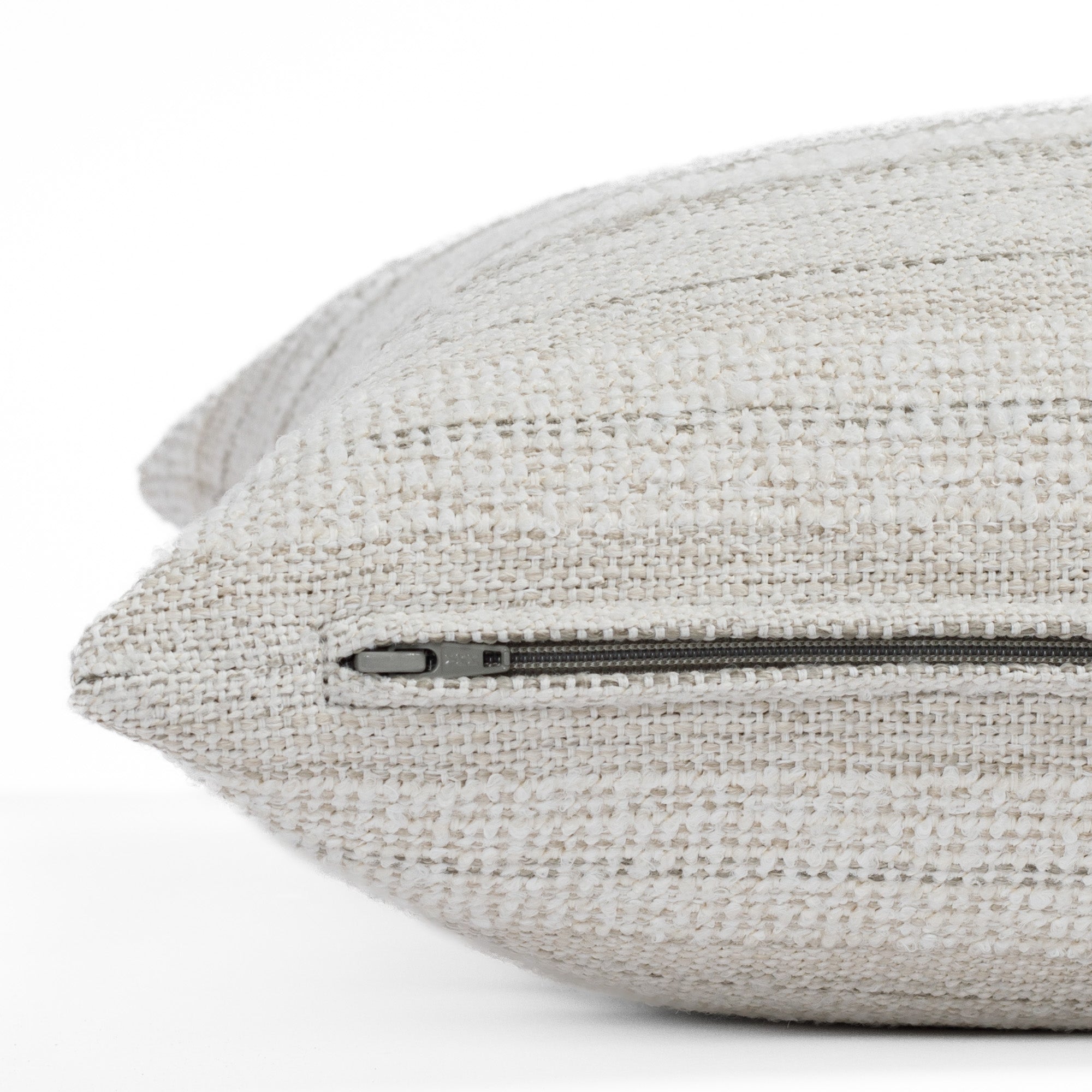 A white and light grey textured toss pillow from Tonic Living: close up zipper view.