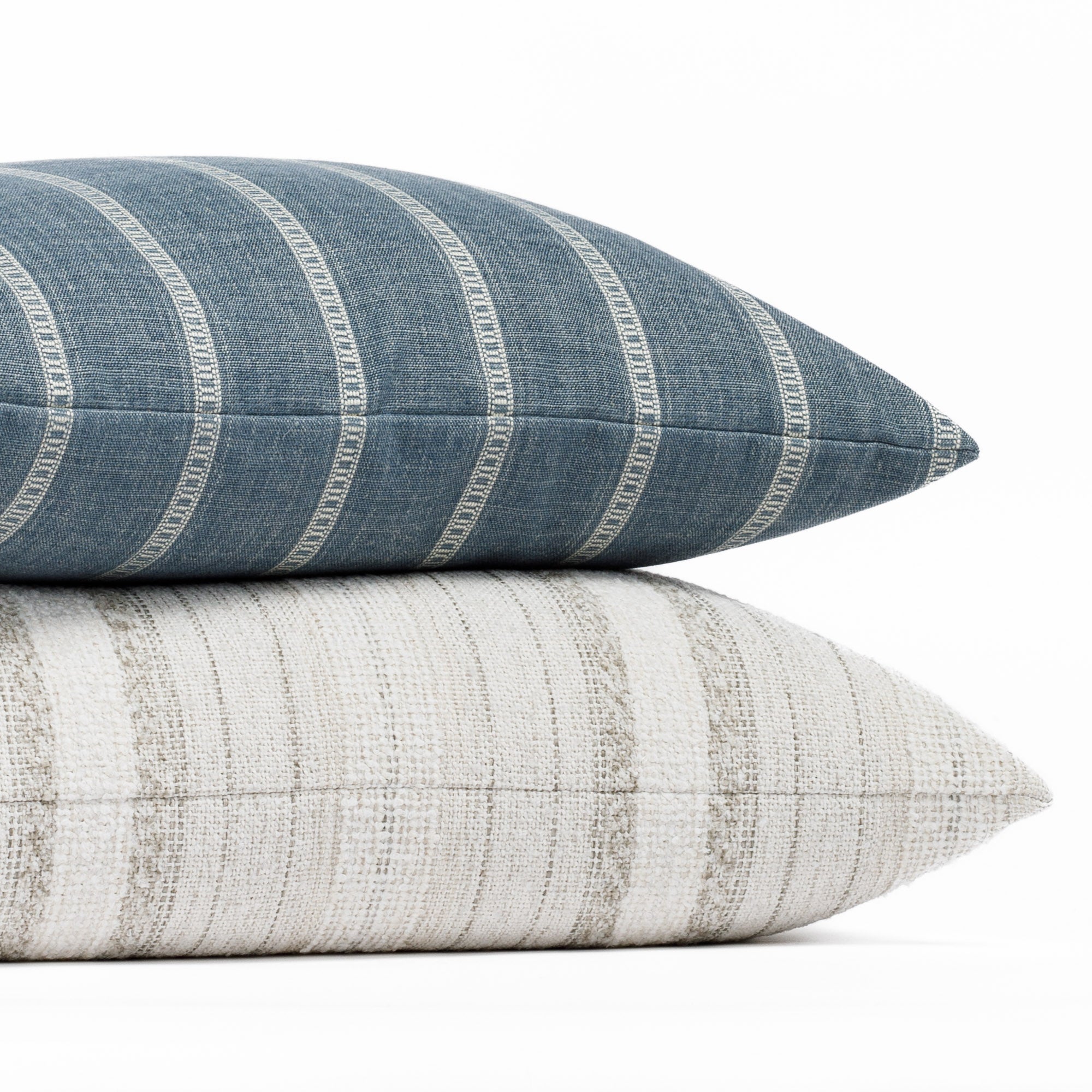 A blue and white striped pillow resting on a neutral striped pillow.