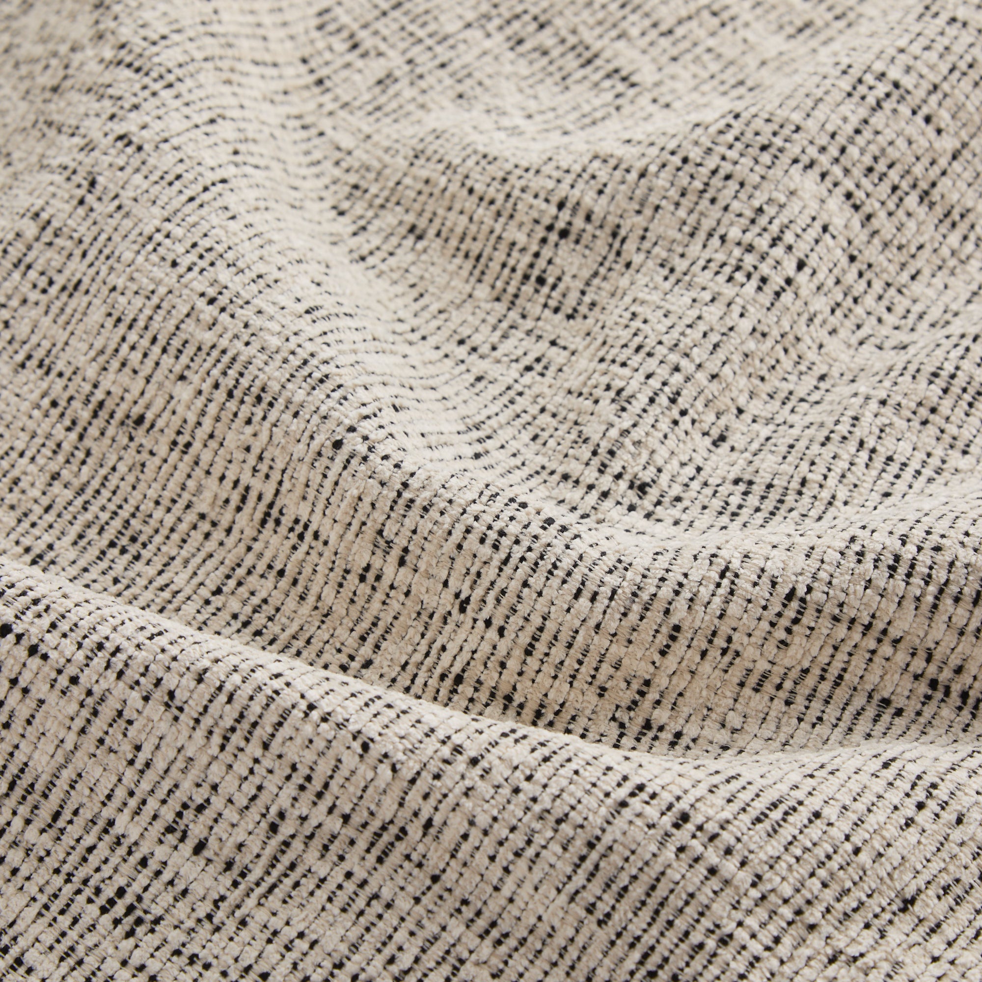 Close up of Atlas Fabric Salt & Pepper, subtle off-white and black textured stripe indoor-outdoor fabric, Tonic Living.