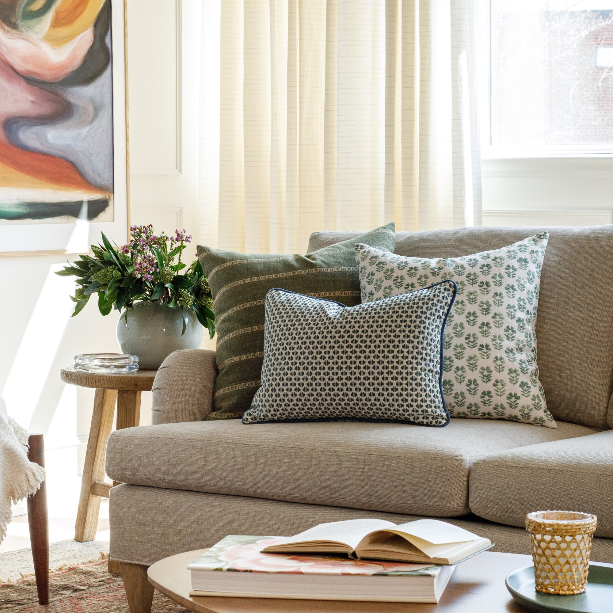 A selection of fresh green designer throw pillows from Tonic Living, styled on a couch.