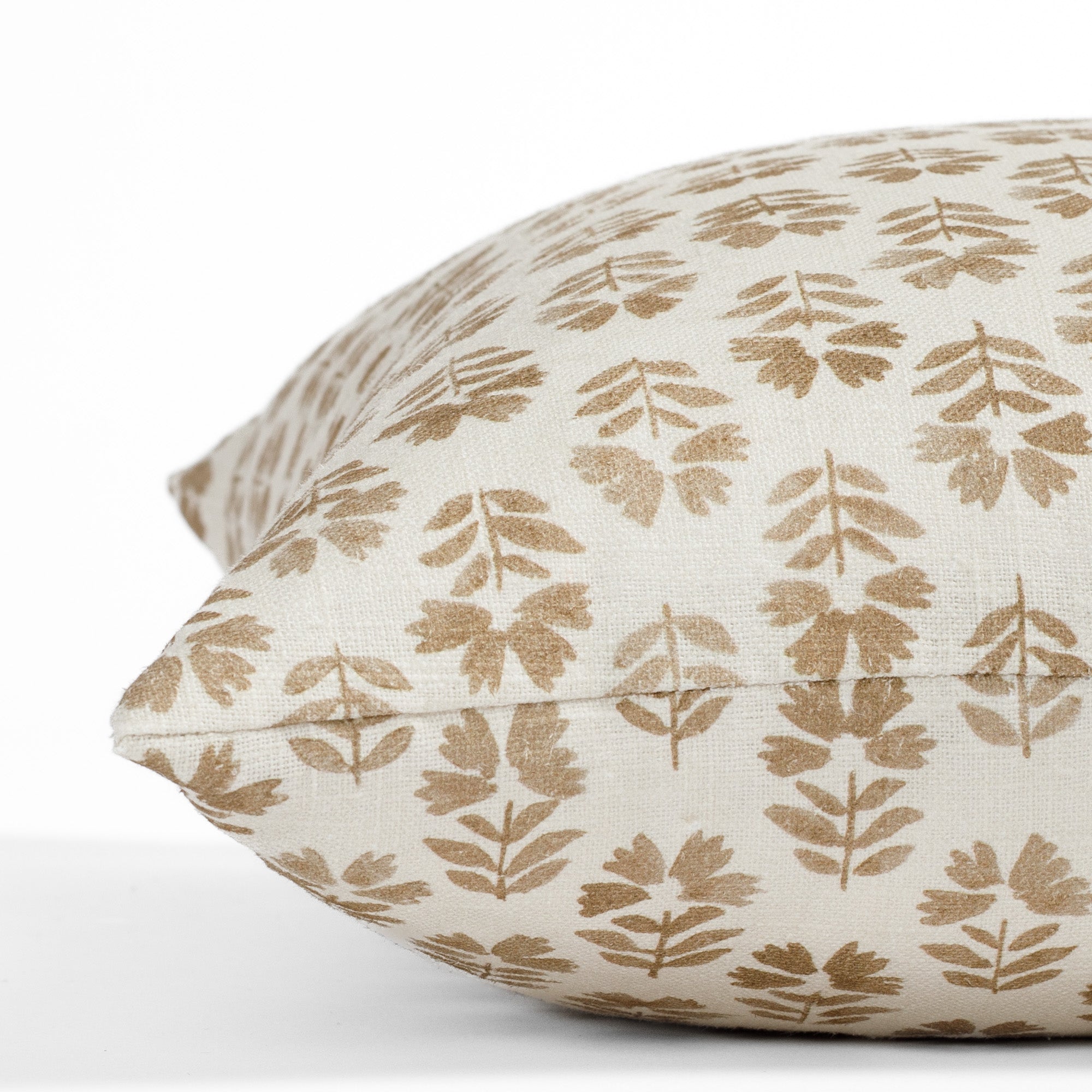 a brown and cream floral block print pillow: close up side view
