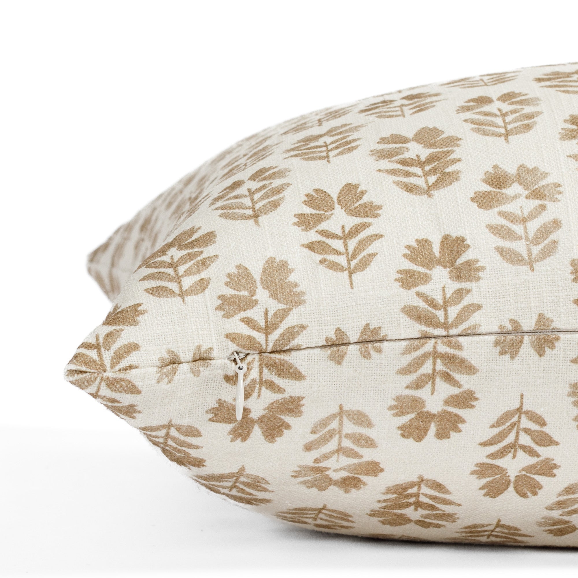 a brown and cream floral block print pillow: close up zipper view