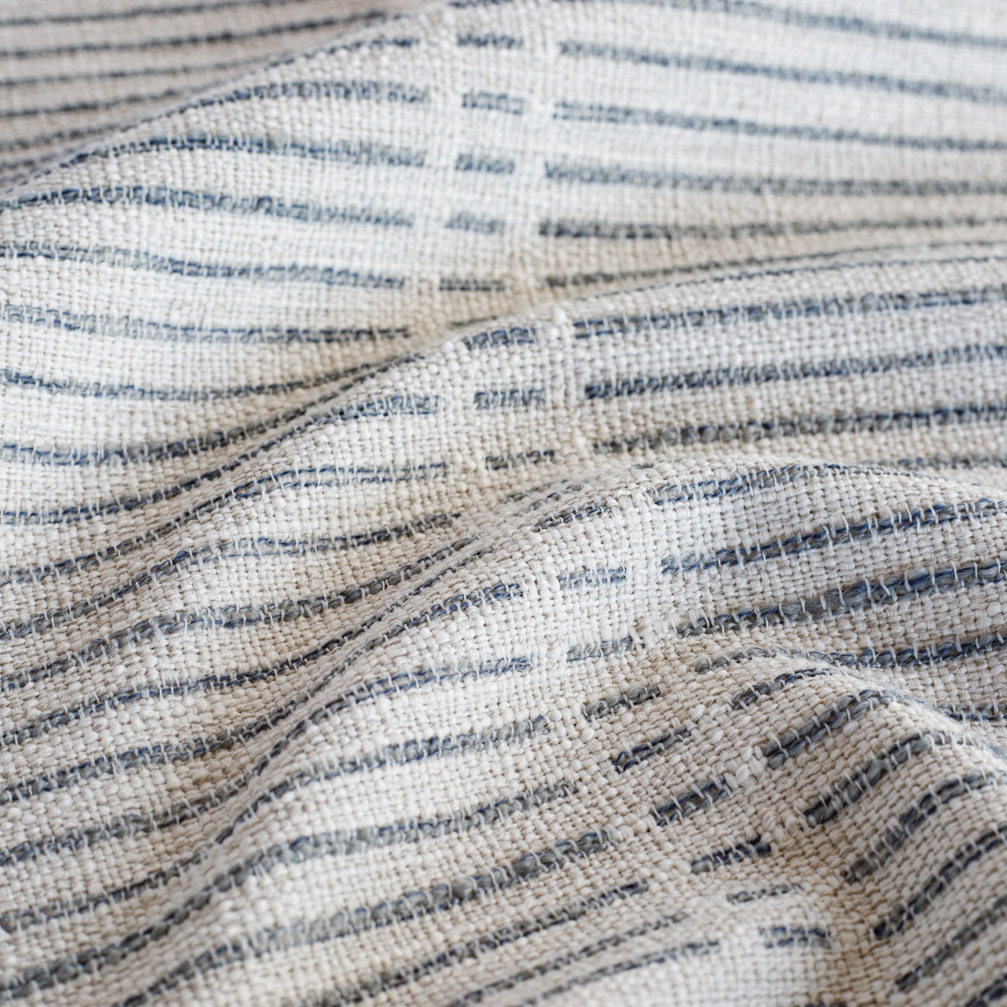 a woven light grey and stone blue dashed stripe patterned upholstery fabric : close up view
