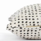 a cream and black polka dot patterned throw pillow : close up zipper view