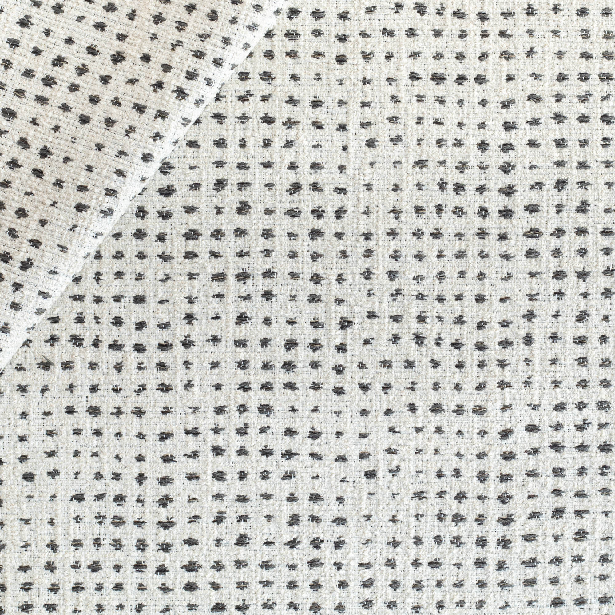 an off-whitee and black variegated polka-dot patterned textured upholstery fabric