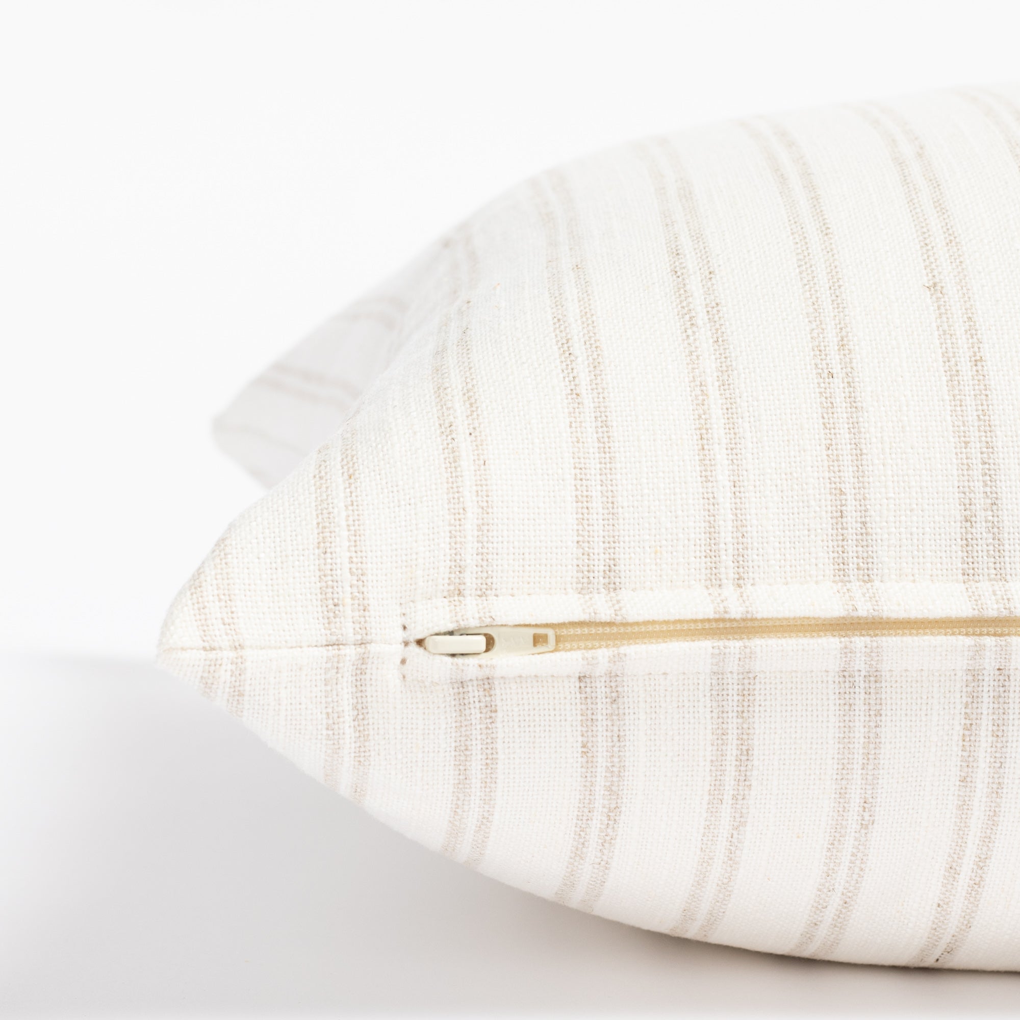 a soft white and beige vertical stripe style throw pillow : close up zipper view