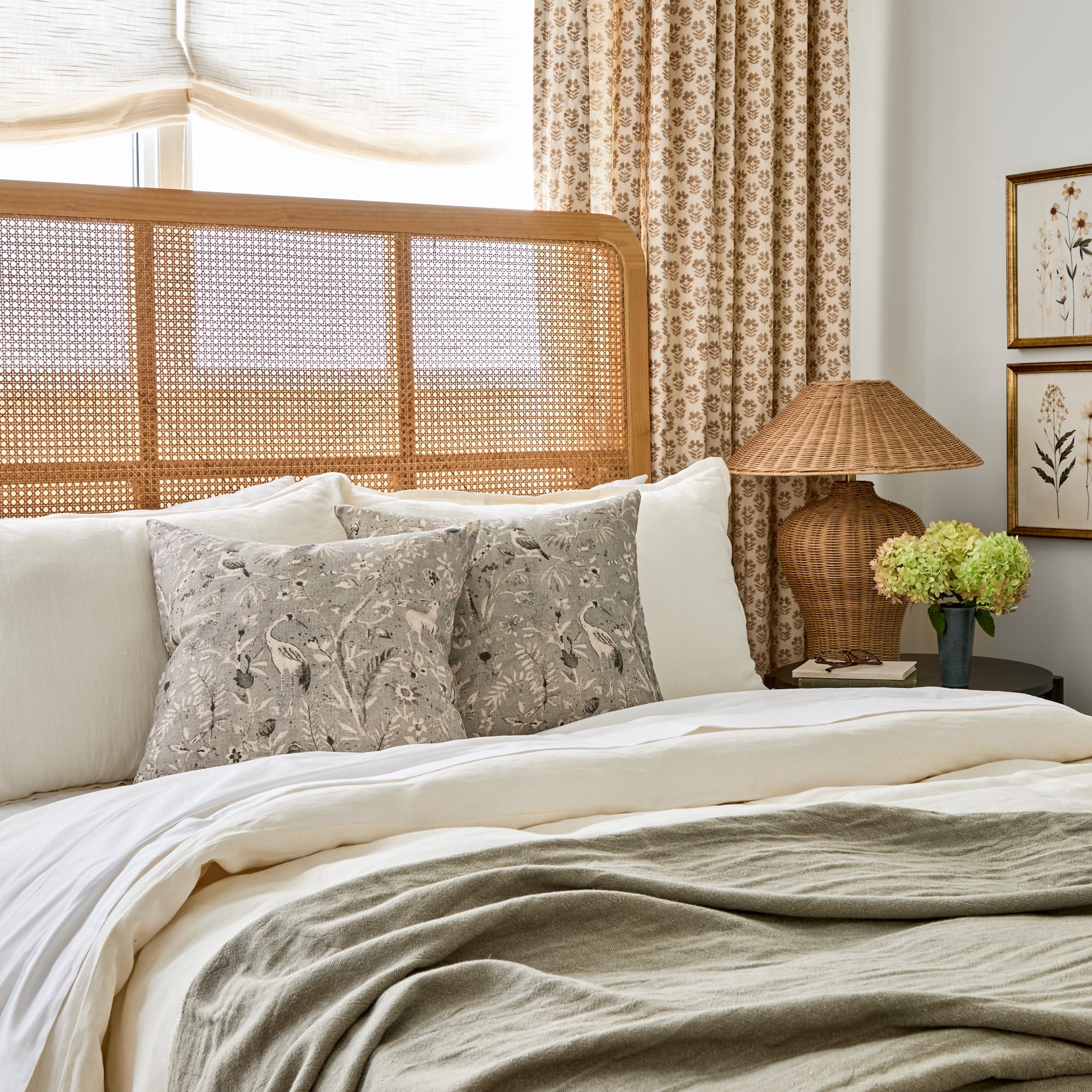 Tonic Living Cyprus smokey blue-grey toss pillow with birds and plants, styled on a layered bed for a cozy bedroom look