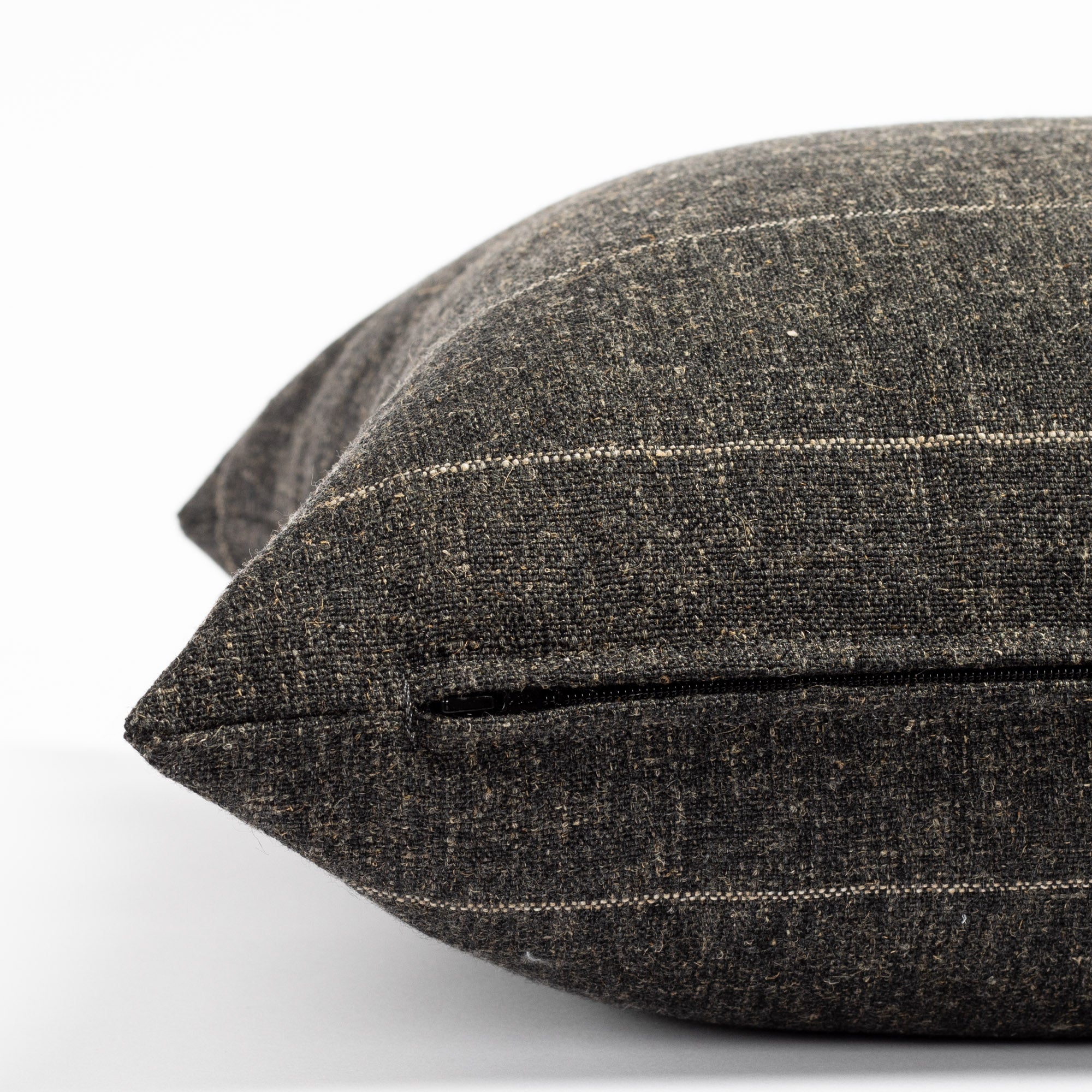 a charcoal grey with a fine beige horizontal stripe throw pillow : close up zipper view