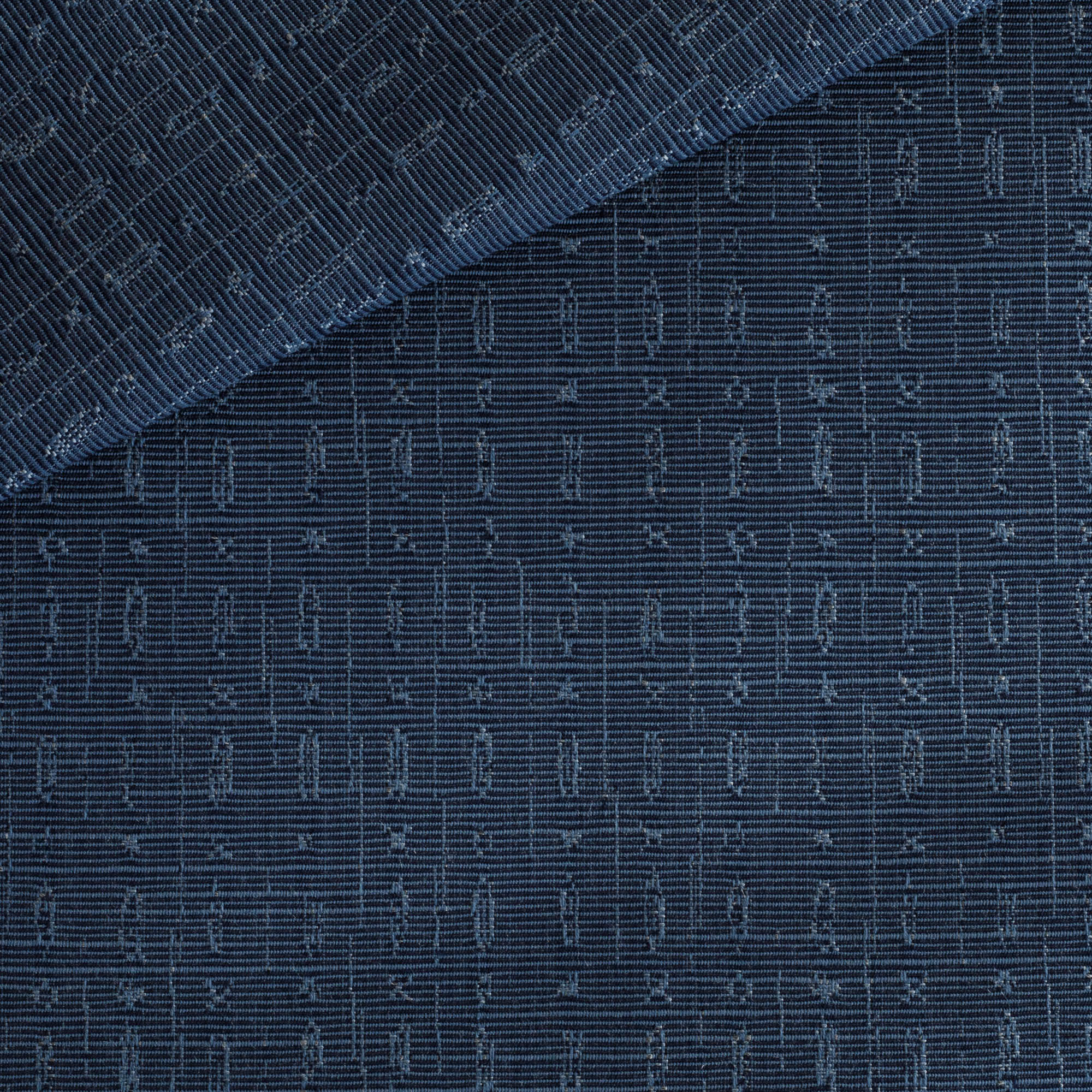 Embrace Indigo, an indoor/outdoor upholstery fabric from Tonic Living, featuring topstitching in an asymmetrical geometric pattern.