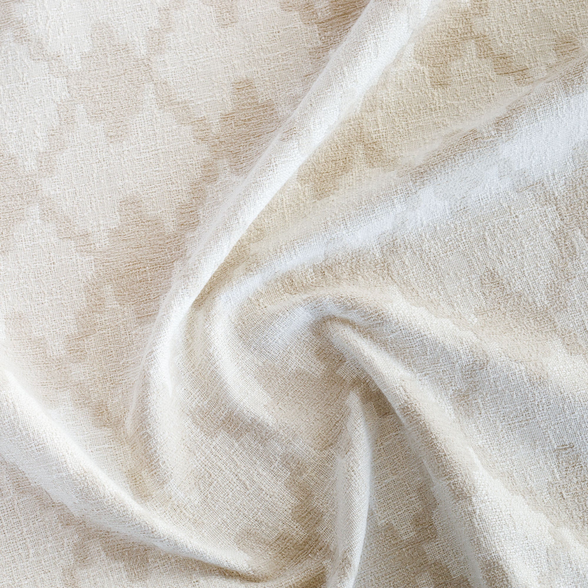 a white and beige geometric tile patterned outdoor upholstery fabric : close up view