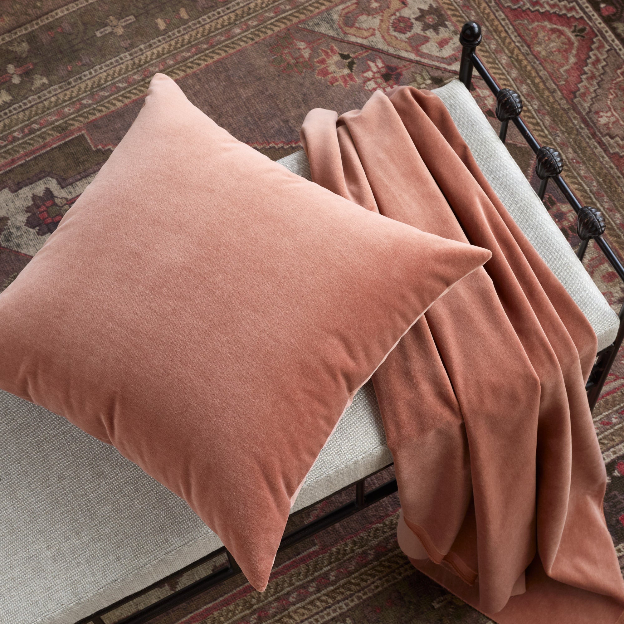Tonic Living Florence Velvet Rosewood cushion styled on a bench with matching peachy pink velvet fabric.