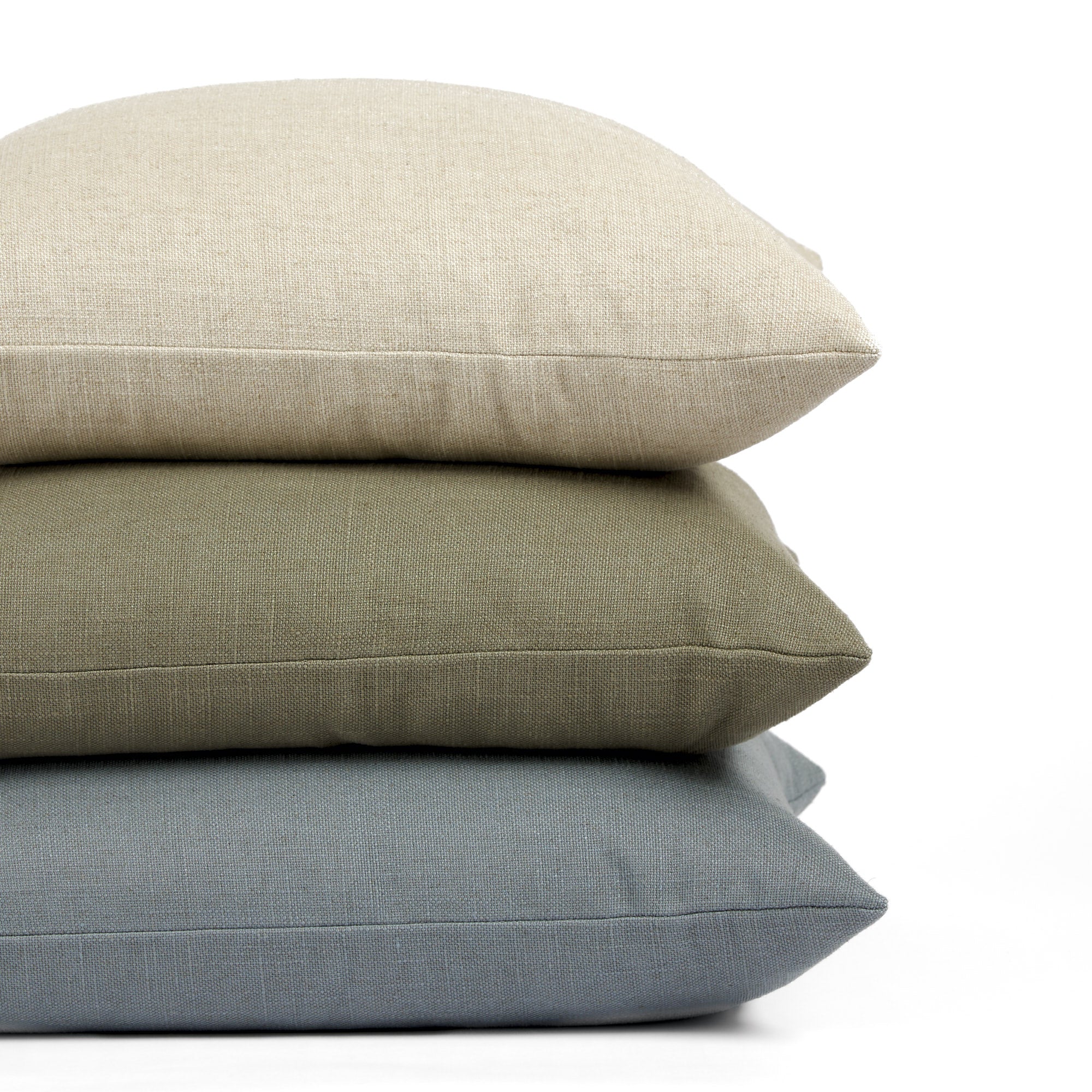 Stack of Tonic Living Hampton 22x22 pillows in Oatmeal, Sage, and Chambray featuring soft linen-look texture.