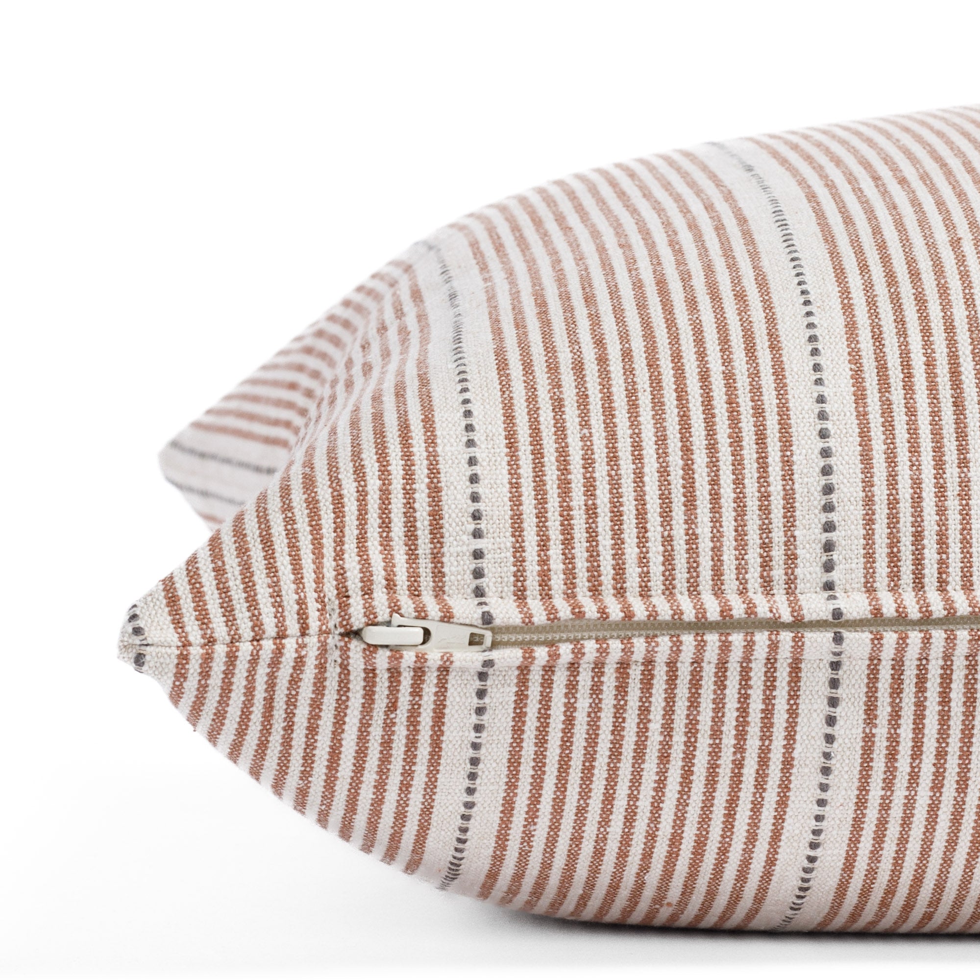 a rust red, cream and black pillow: close up zipper view