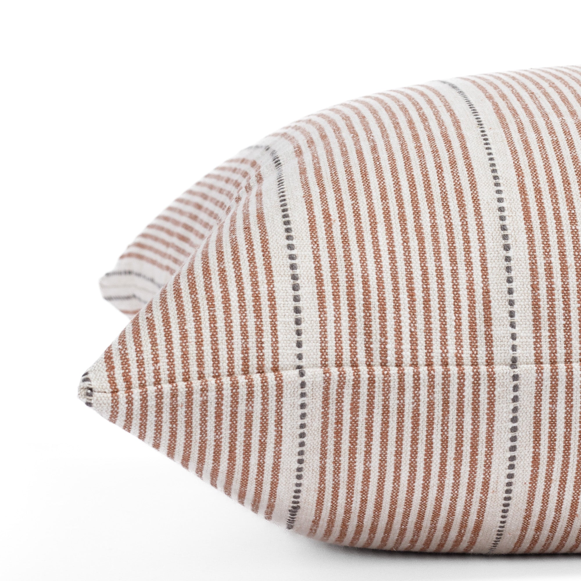 a rust red, cream and black pillow: close up side view