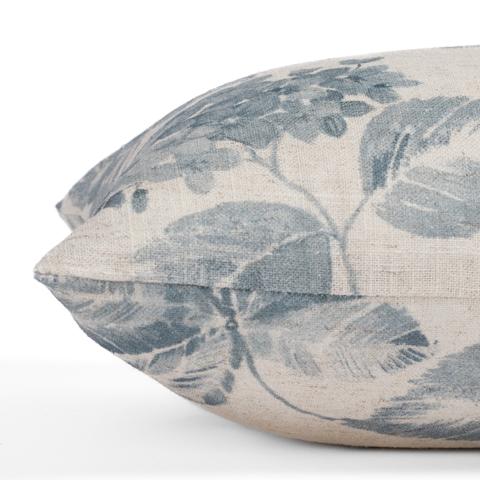 Detailed side close-up of the Heather Indigo lumbar pillow from Tonic Living, emphasizing the vintage-inspired floral design and fabric quality in a soft, dusty blue and beige palette.