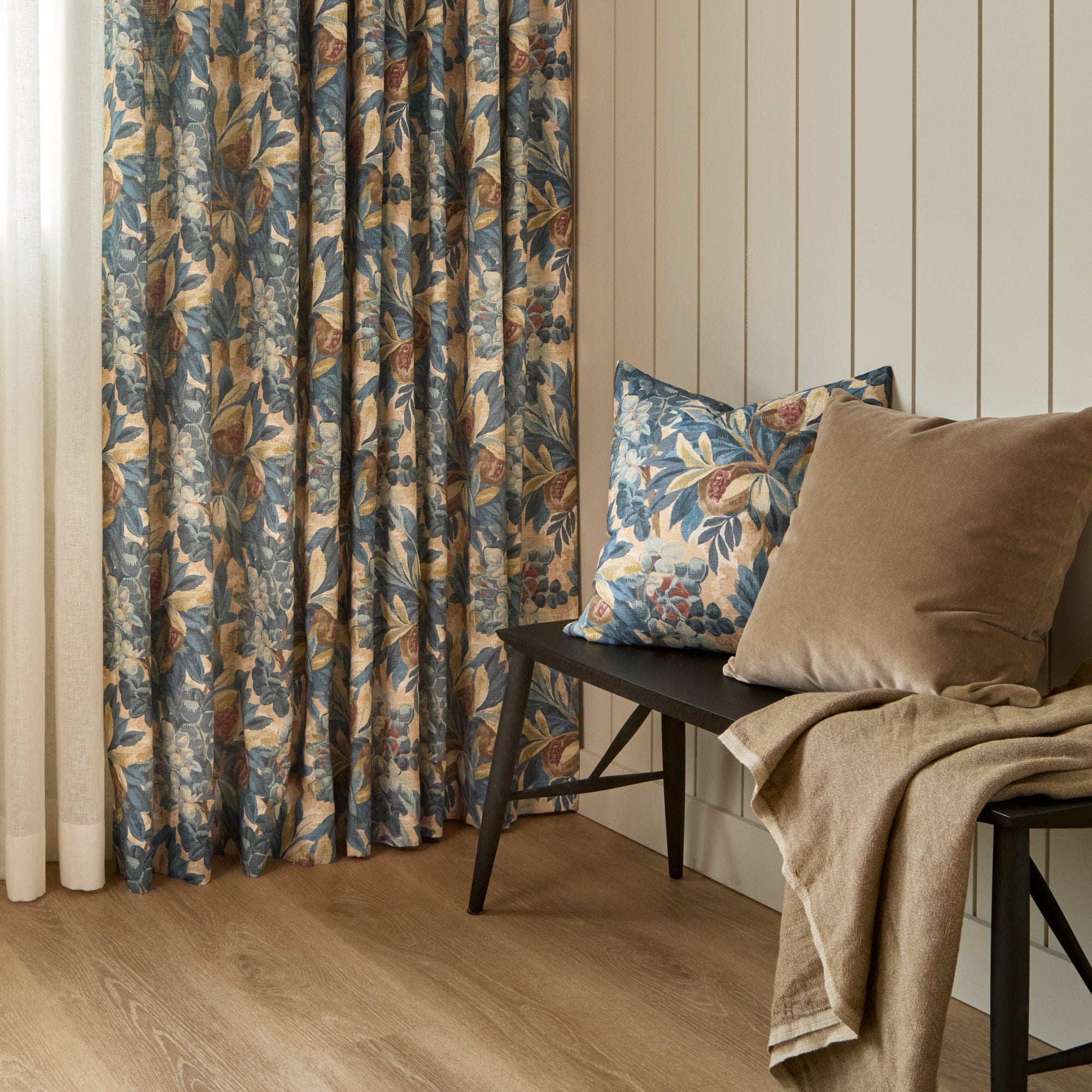 Juno 20x20 Pillow, Navy by Tonic Living styled on a bench with Valentina Velvet Pillow, Toffee, in front of matching Juno Navy floral drapery fabric.