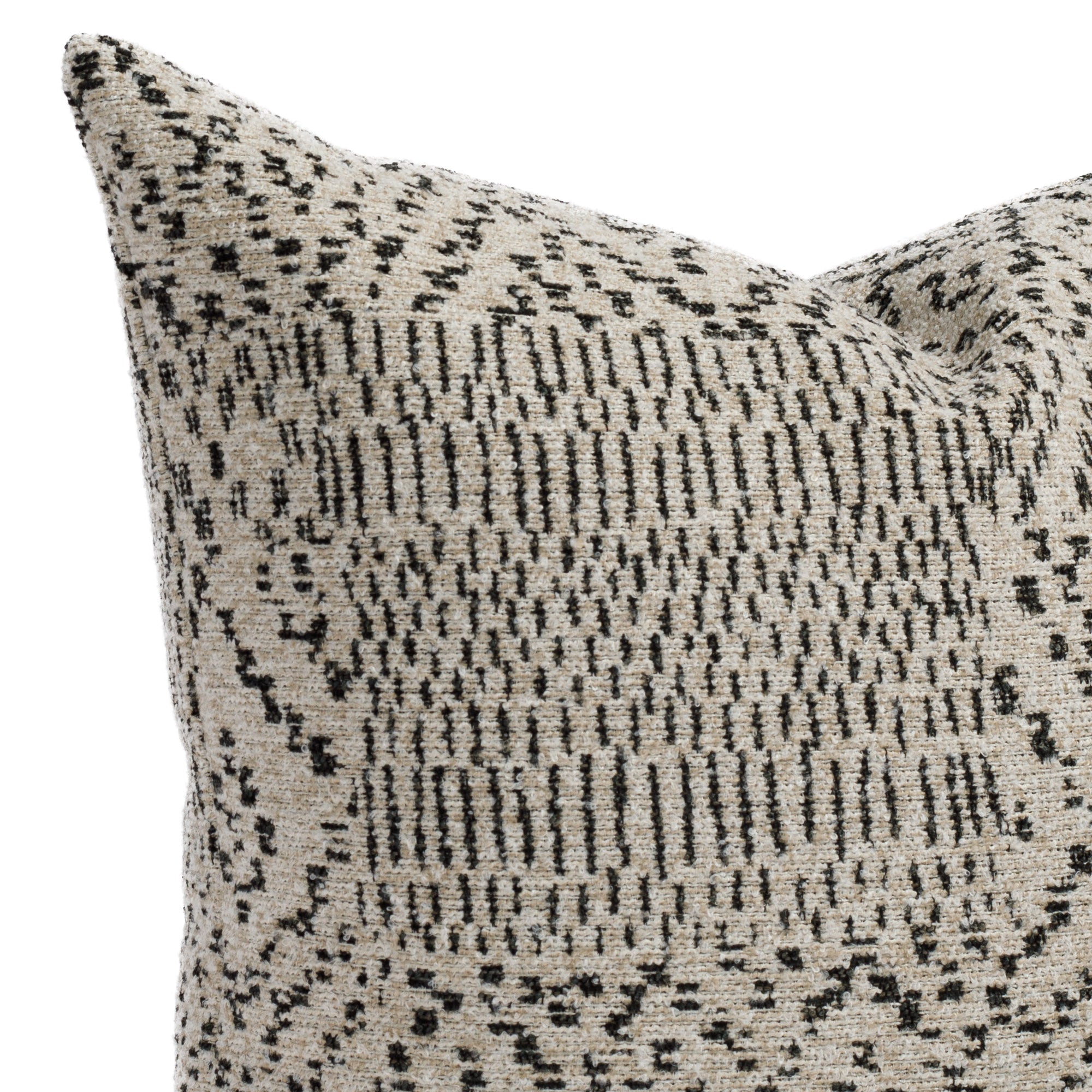 A tan and black throw pillow with an ikat-inspired design: close up view.