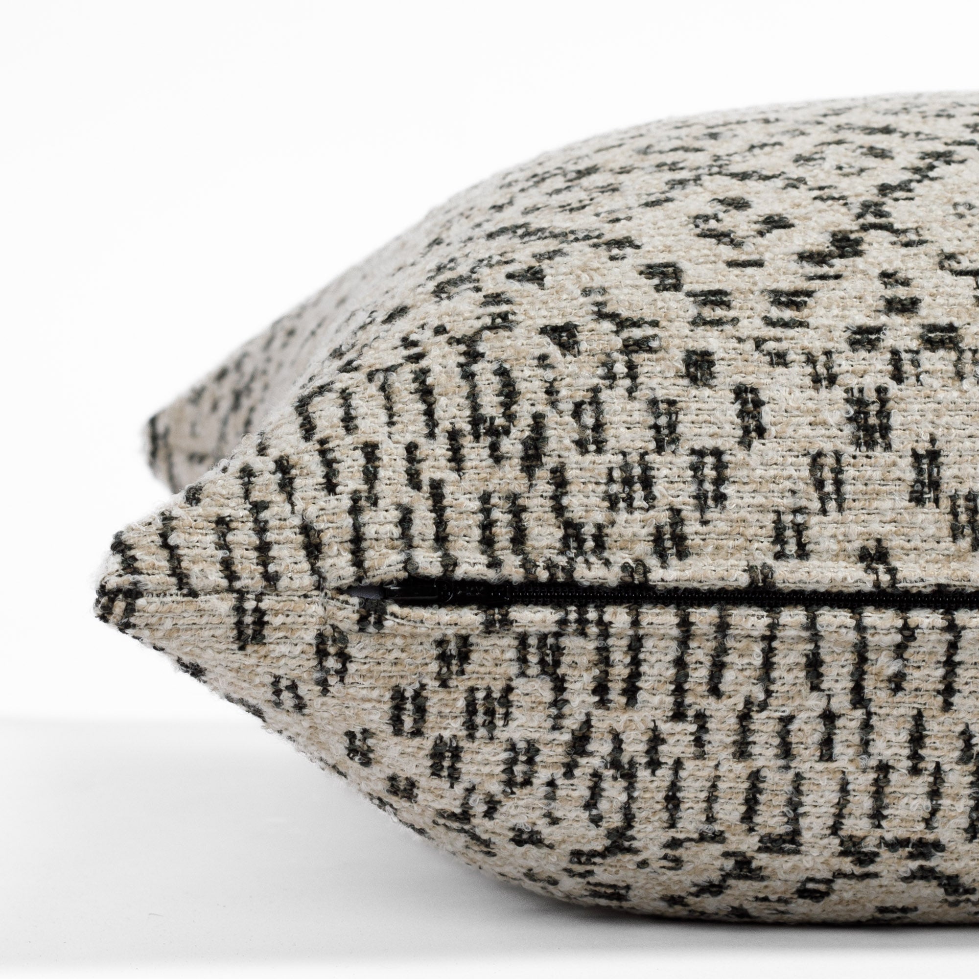 An earthy oatmeal and black textured pillow from Tonic Living: close up zipper view.
