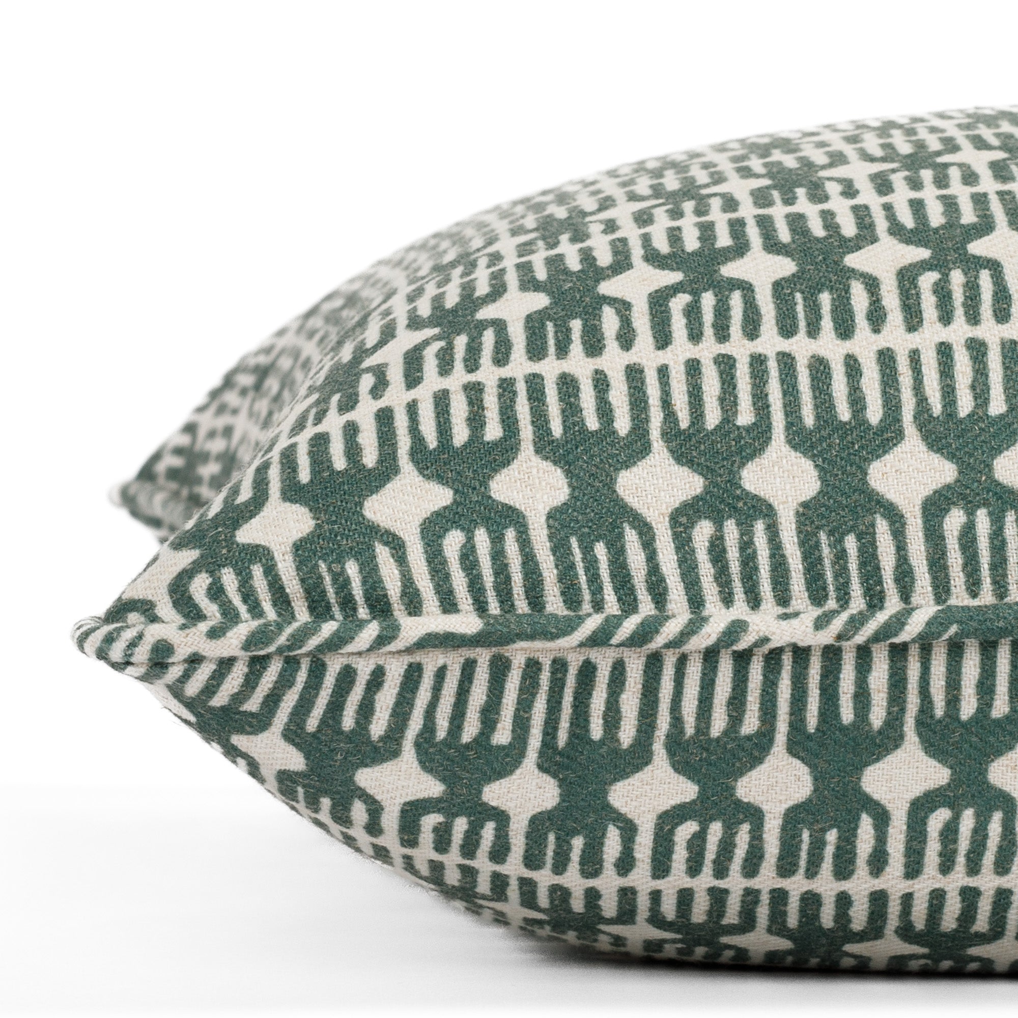 Close-up side view of a green and beige pillow with piped detail and modern organic pattern (Meadow Emerald 20x20 pillow from Tonic Living).
