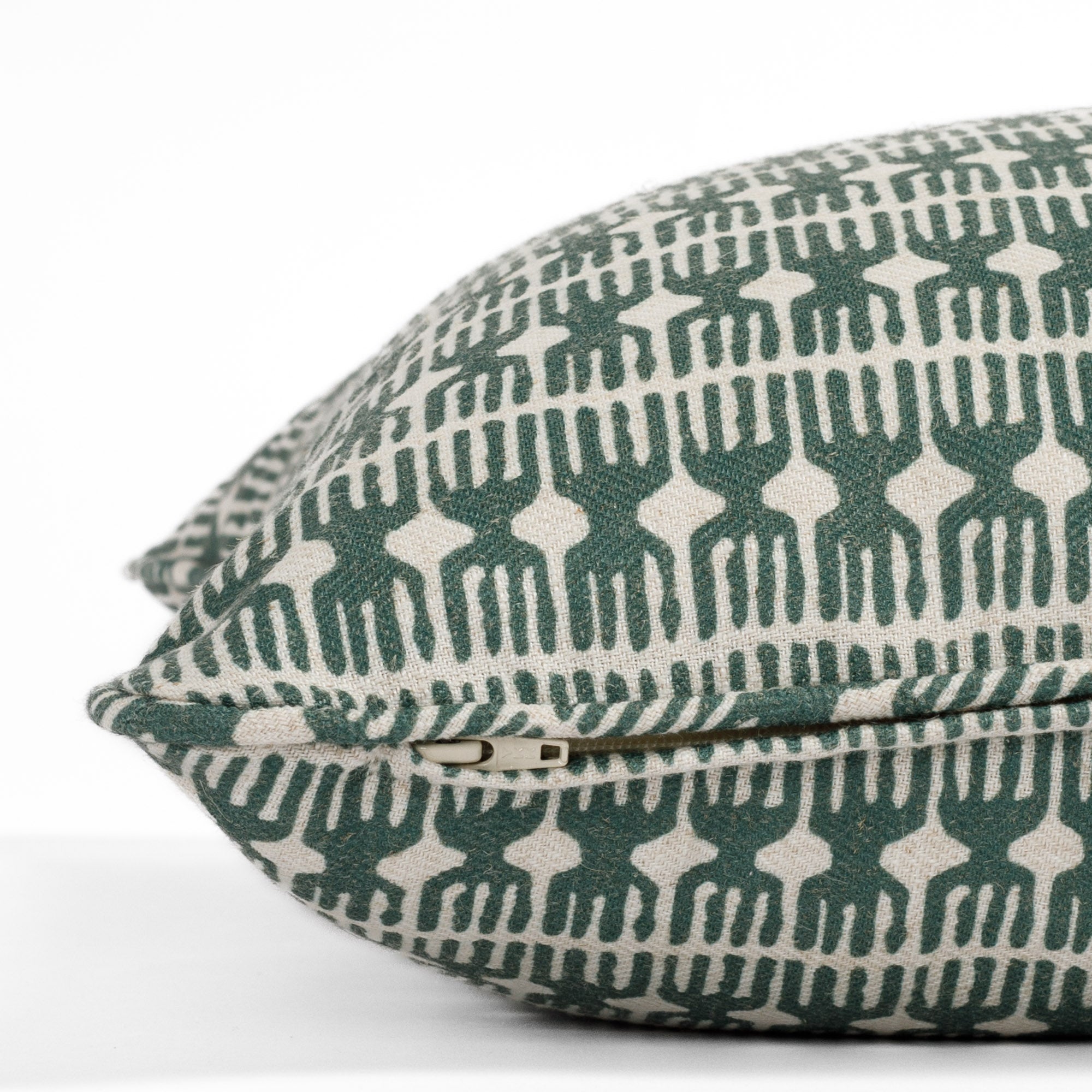 Close-up zipper view of a green and natural pillow with piped detail and global organic pattern (Meadow Emerald 20x20 pillow from Tonic Living).