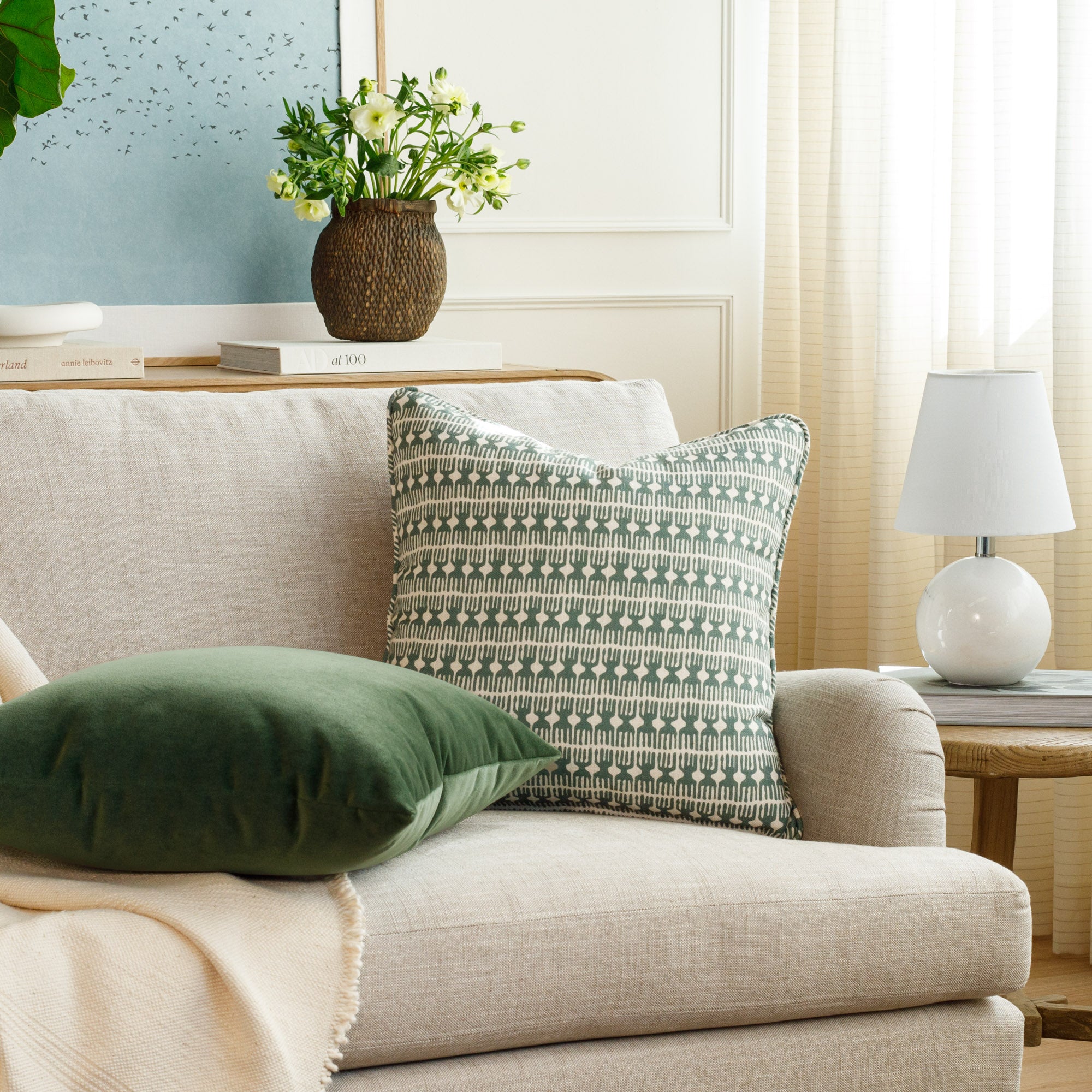 Meadow Emerald 20x20 green and white throw pillow with bold block print, styled on a sofa in a modern living room alongside Valentina Velvet Pine pillow by Tonic Living.