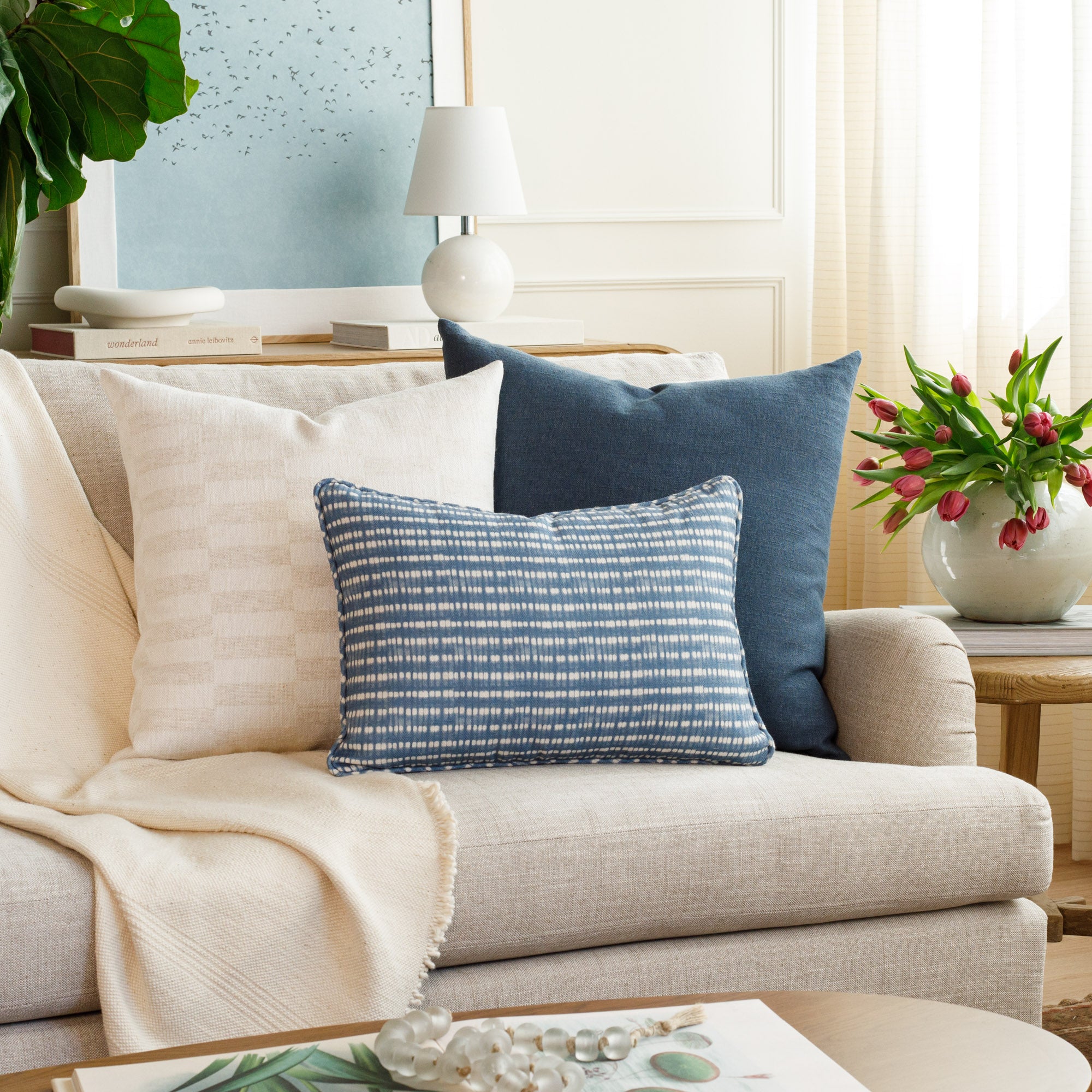A selection of designer blue & white throw pillows from Tonic Living, styled in a beautiful living room.