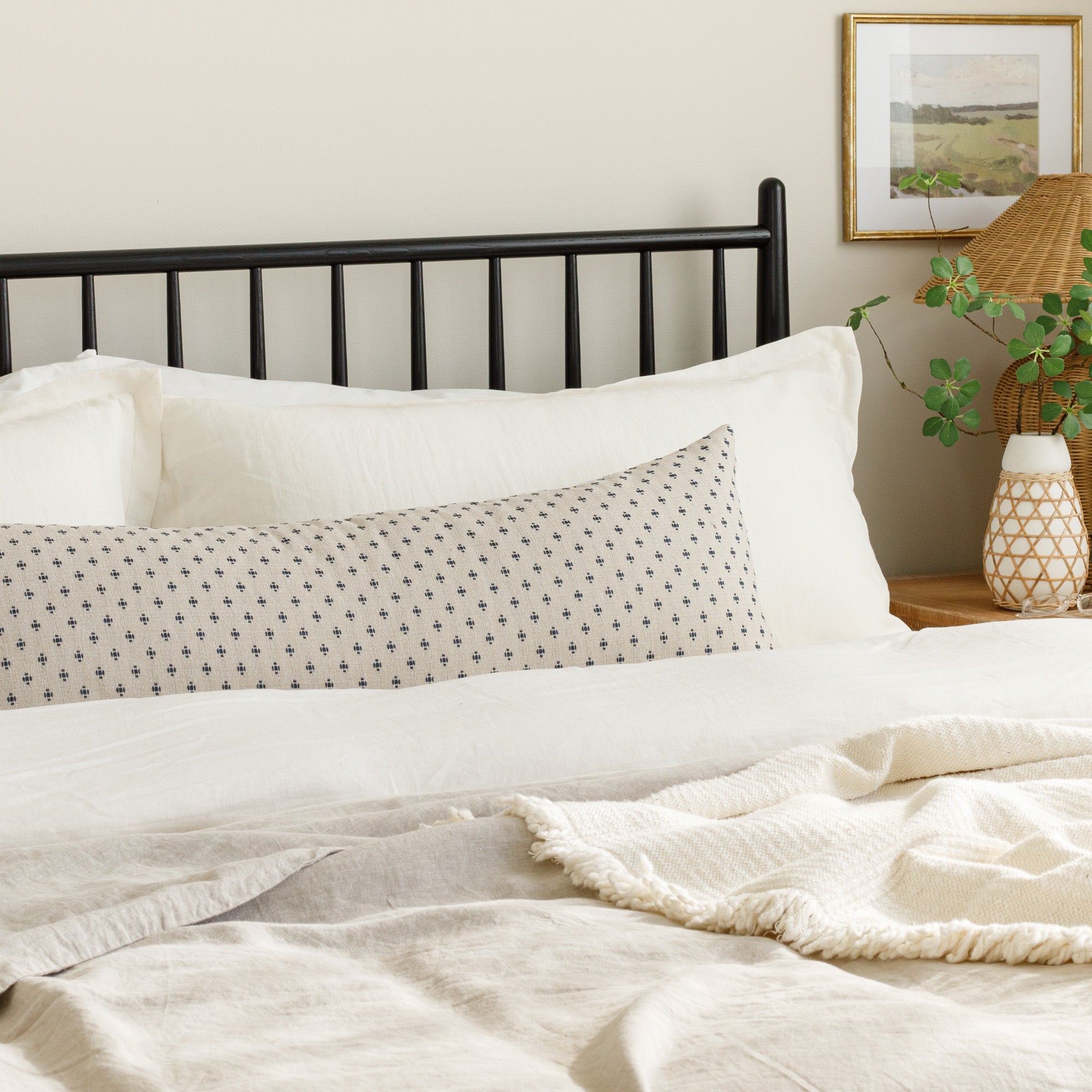 Pierce Navy, an extra large bed bolster pillow from Tonic Living, featuring a timeless beige and navy dotted pattern, styled on a bed.