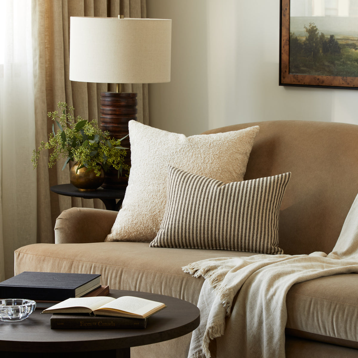 Tonic Living Rupert Parchment bouclé pillow styled on a sofa with a brown and beige striped lumbar cushion.