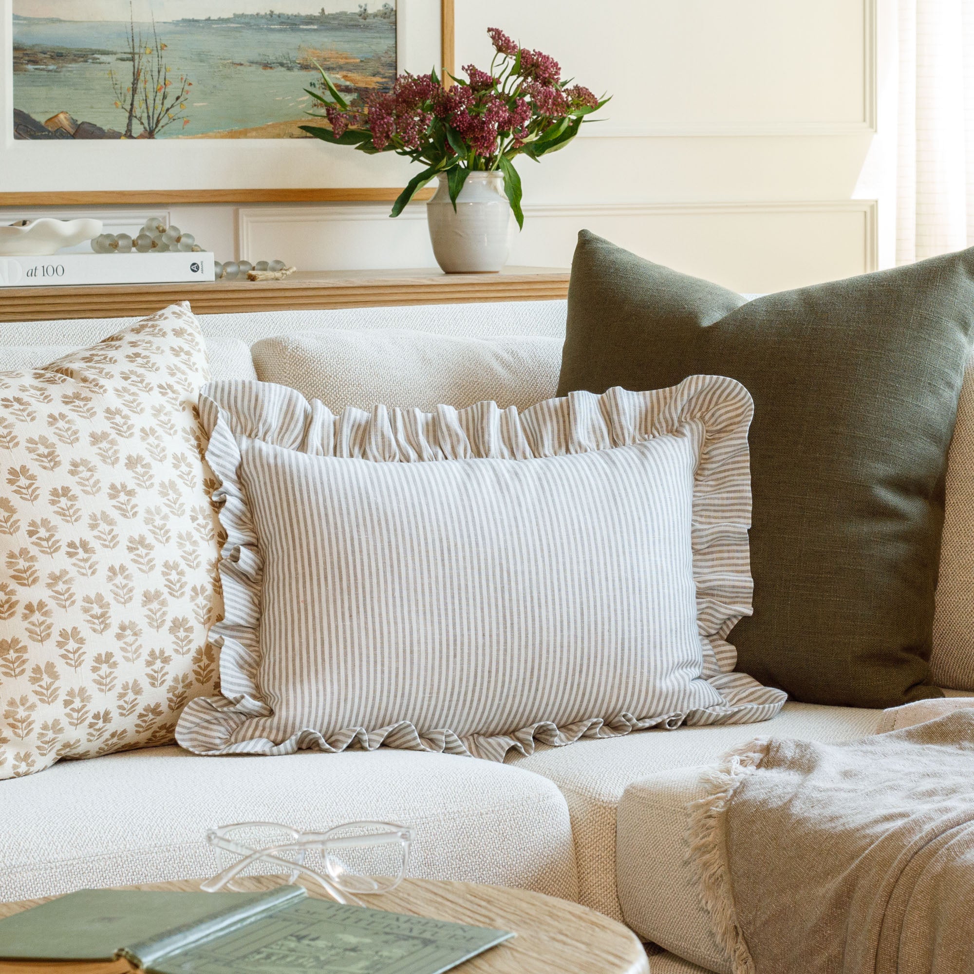 Styled shot of three designer throw pillows by Tonic Living on a sofa, including the Siena Buff lumbar pillow paired with earthy tones of green, umber, and cream for a layered, cozy look.