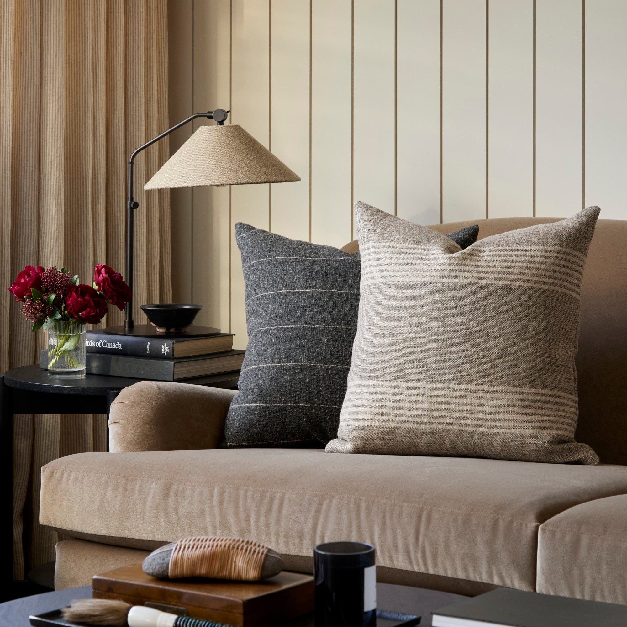 Earthy striped throw pillows from Tonic Living, styled on a rich velvet sofa.