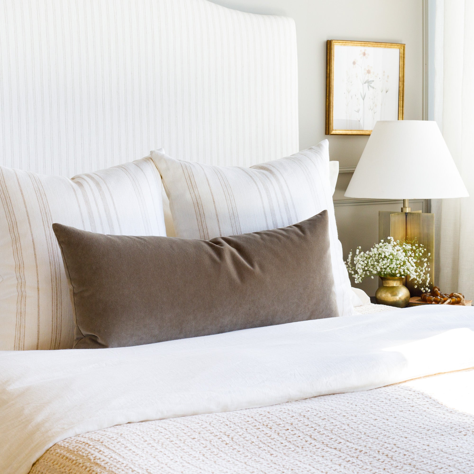 Neutral bedroom styled with white & beige striped pillows + brown velvet lumbar