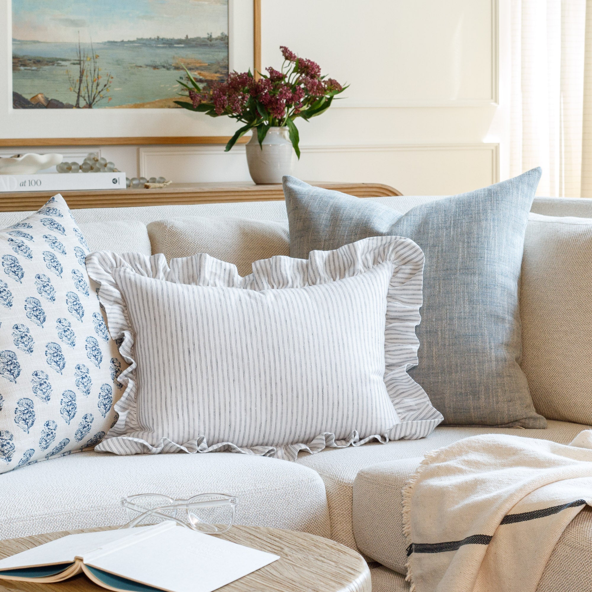 Styled shot of three decorative throw pillows by Tonic Living on a sofa, including the Verona Jet lumbar cushion paired with crisp blues and whites for a fresh, designer-approved look.