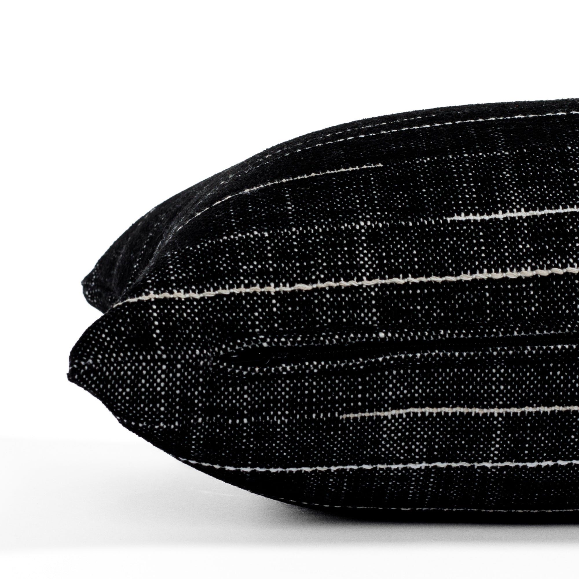 Yuzu Onyx, a black and white lumbar pillow from Tonic Living, showcasing a dappled texture accented with organic white lines: close-up zipper view.