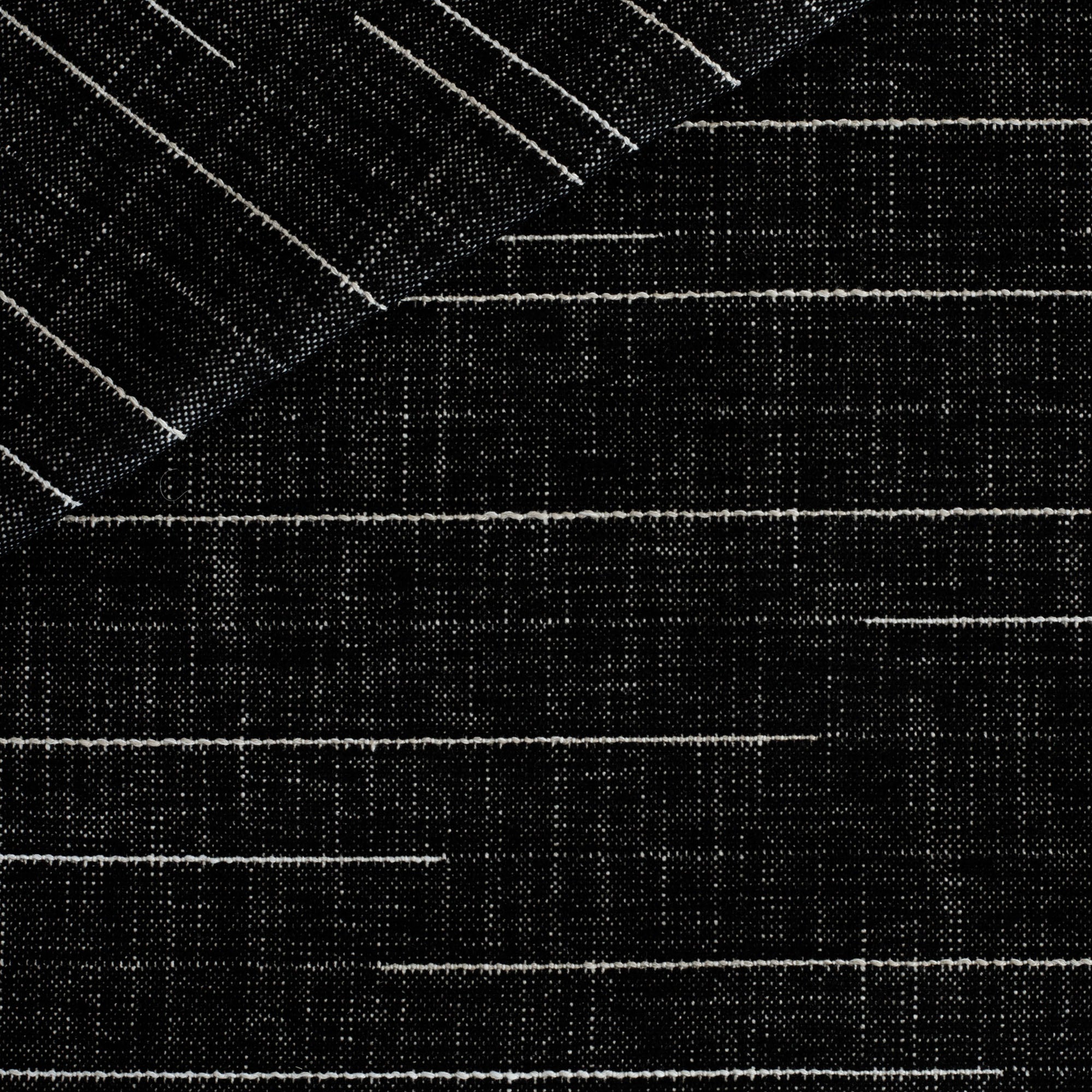 Yuzu Onyx, a black indoor/outdoor fabric from Tonic Living with raised white stitching.