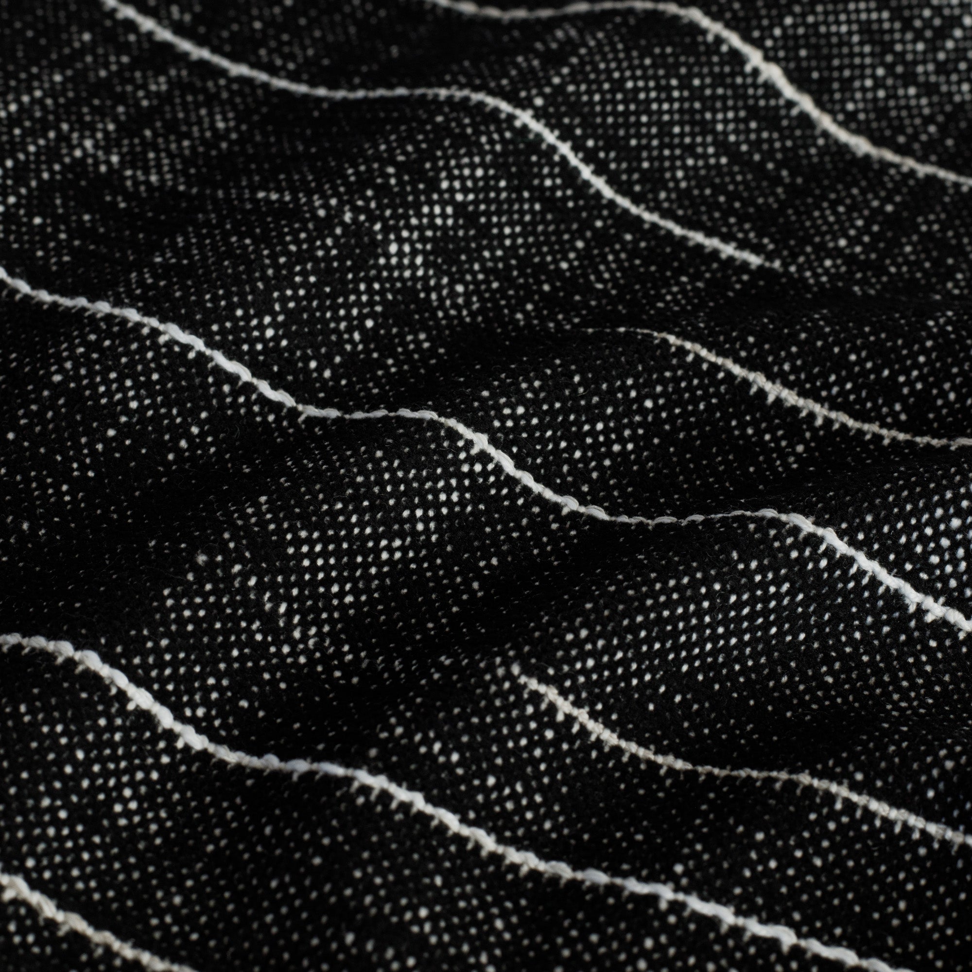 Yuzu Onyx, a black indoor/outdoor fabric with contrasting white broken stripes: close up view.