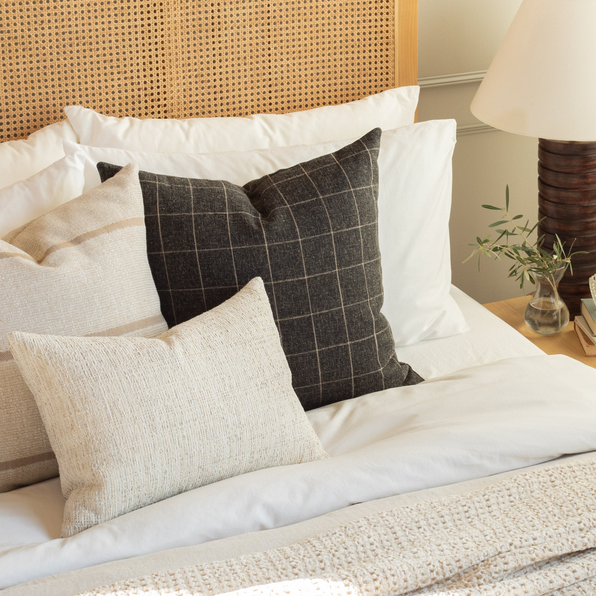 Tonic Living Dundee Sable 22x22 Pillow styled on a bed with neutral, textured decorative cushions.