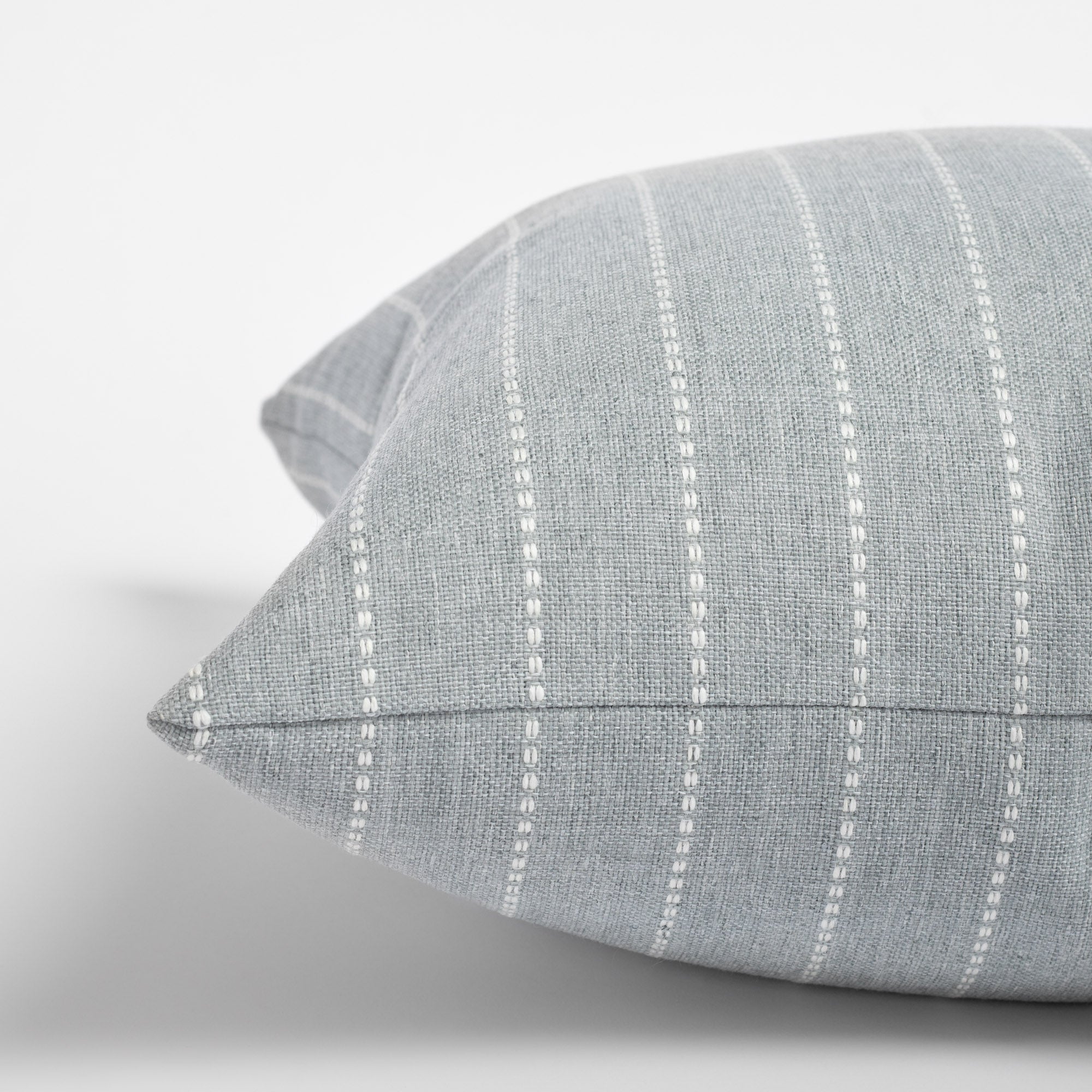 Fontana Cloud 20x20 pillow, a pale blue gray and white vertical stripe indoor outdoor pillow : close up side view