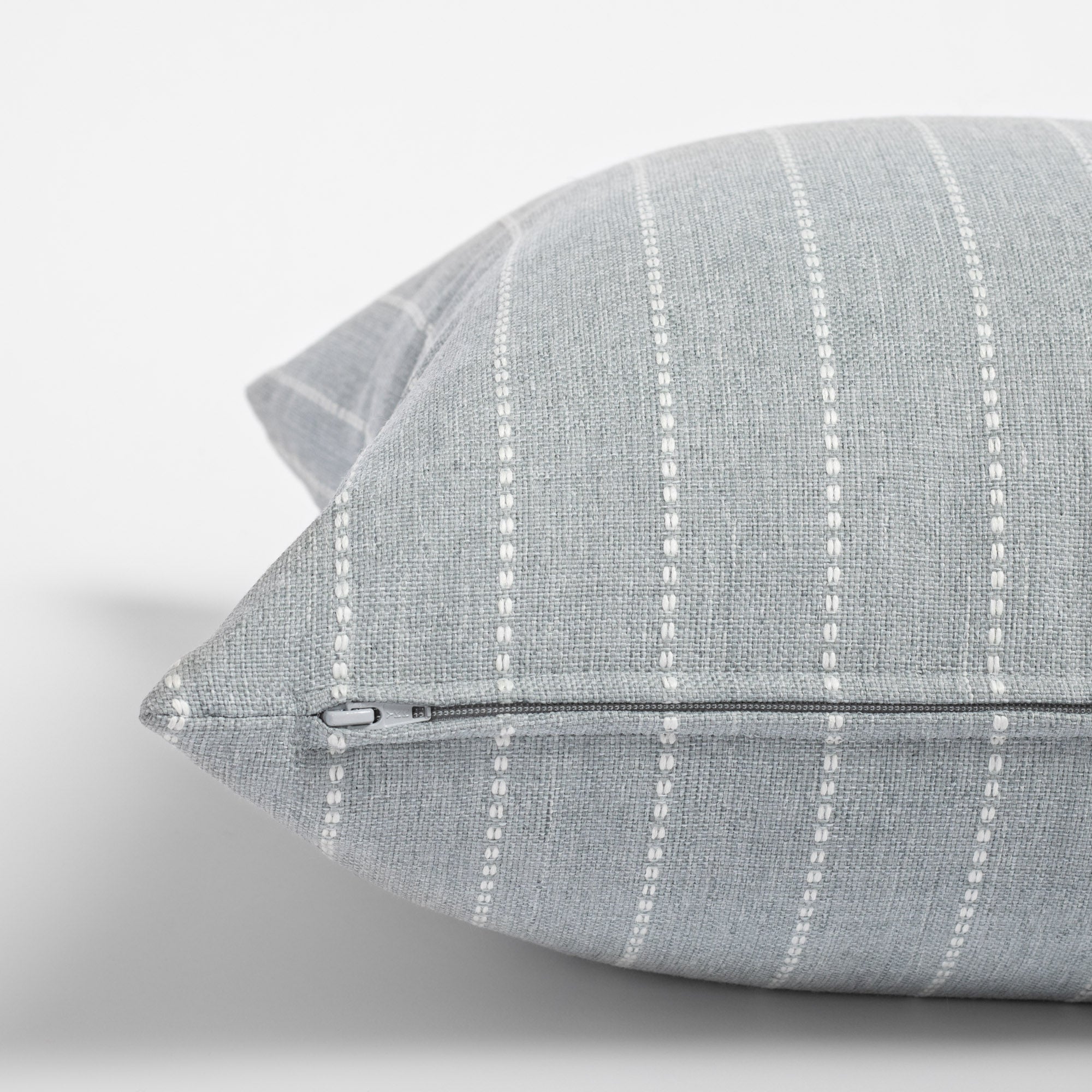 Fontana Cloud 20x20 pillow, a pale blue gray and white vertical stripe indoor outdoor pillow : close up side view