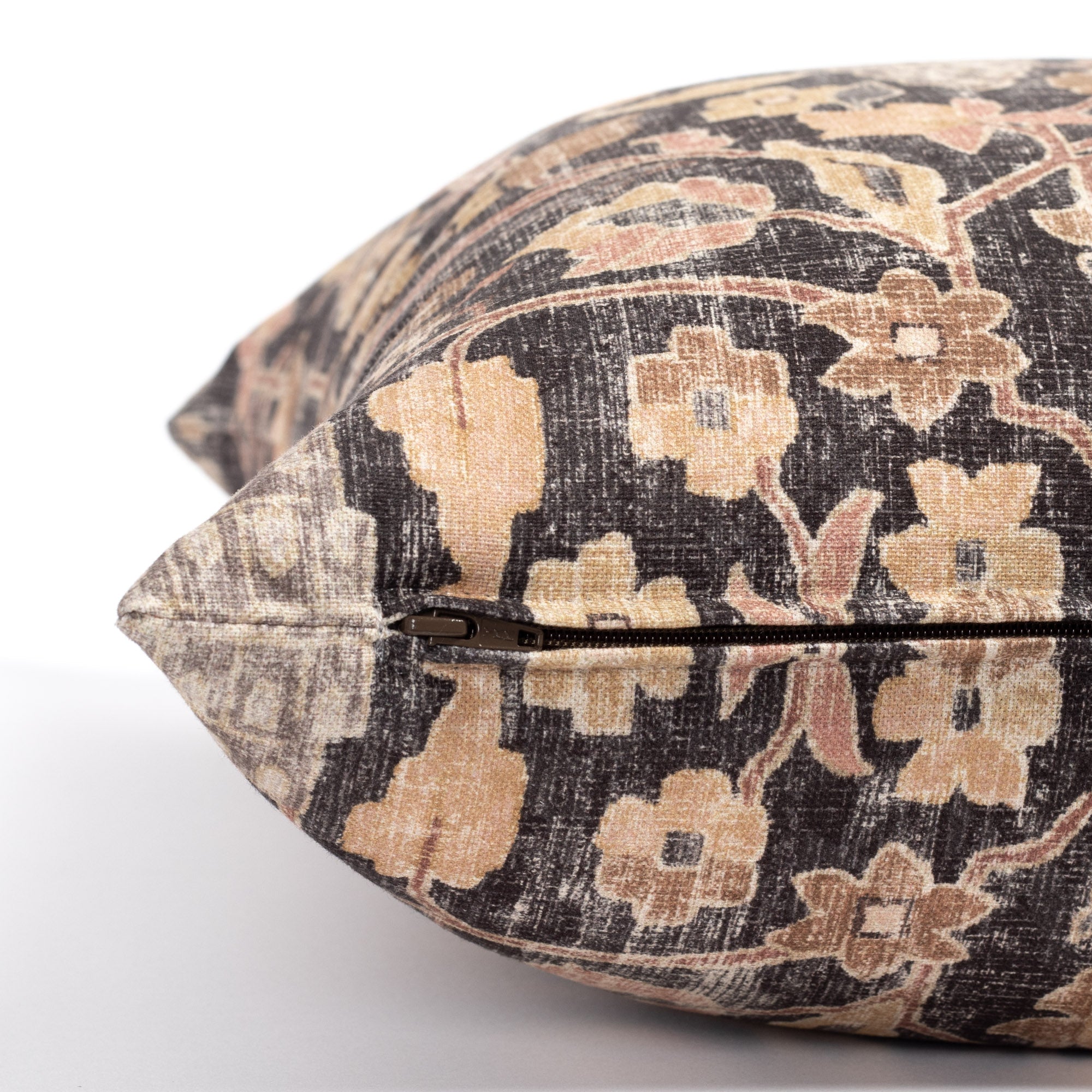 a faded black and earth toned vintage floral tapestry print decorative pillow : close up zipper view