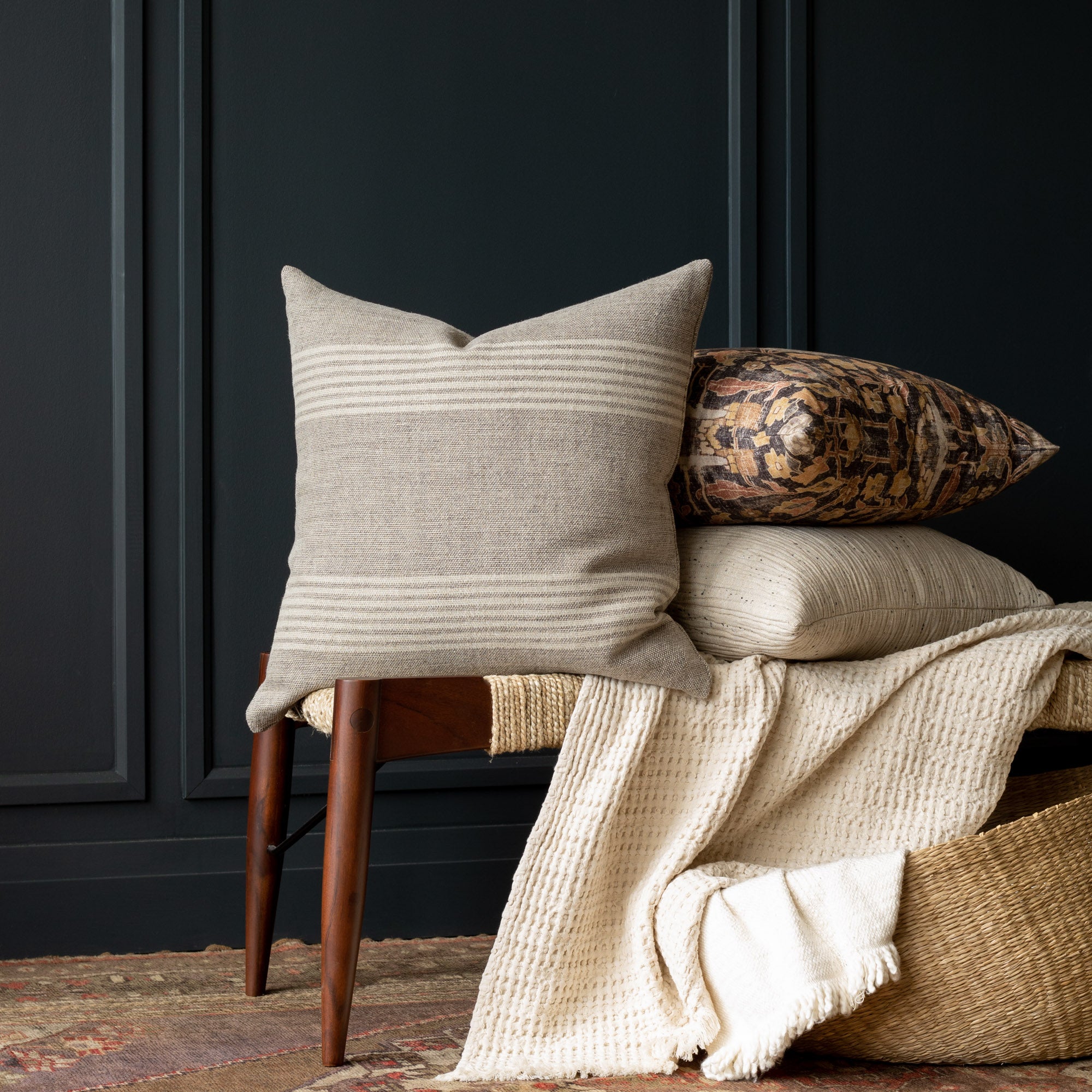 Stockton Stripe Graphite, a linen throw pillow, in shades of natural tan and faded black stacked with Khalida walnut and Dunes natural