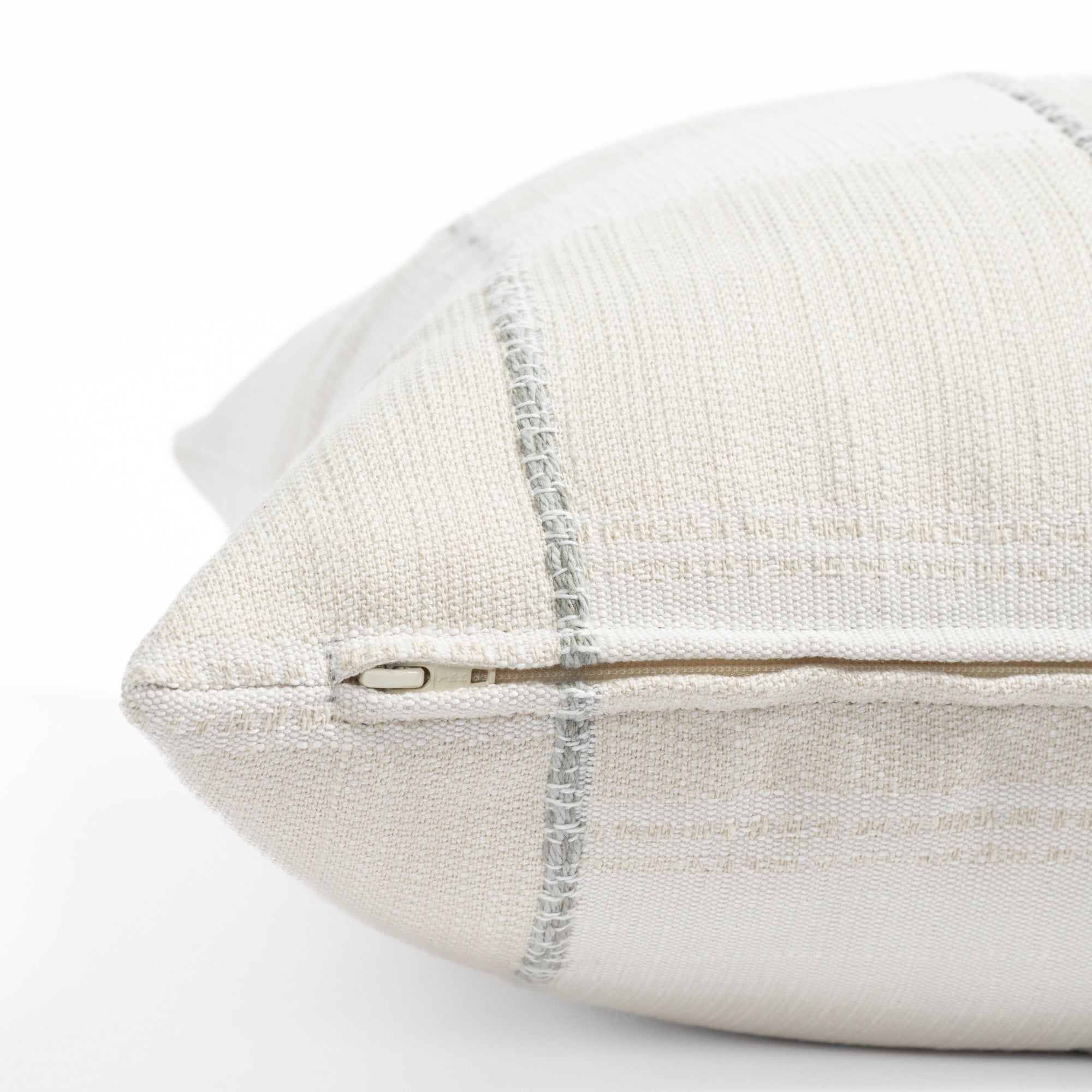 a chunky light blue stripe and white cream patchwork patterned throw pillow : close up zipper view