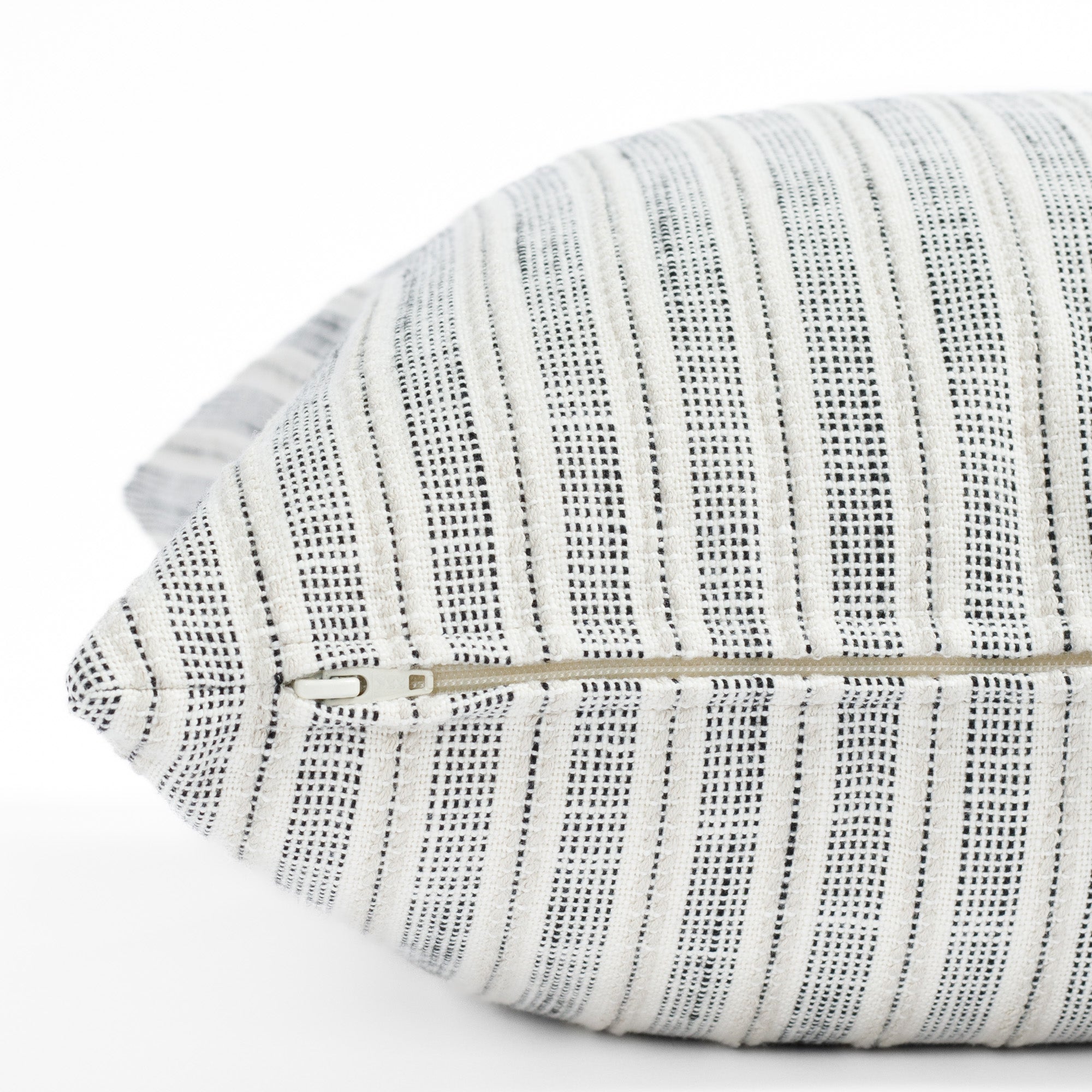 a cream and black stripe outdoor pillow : close up zipper view