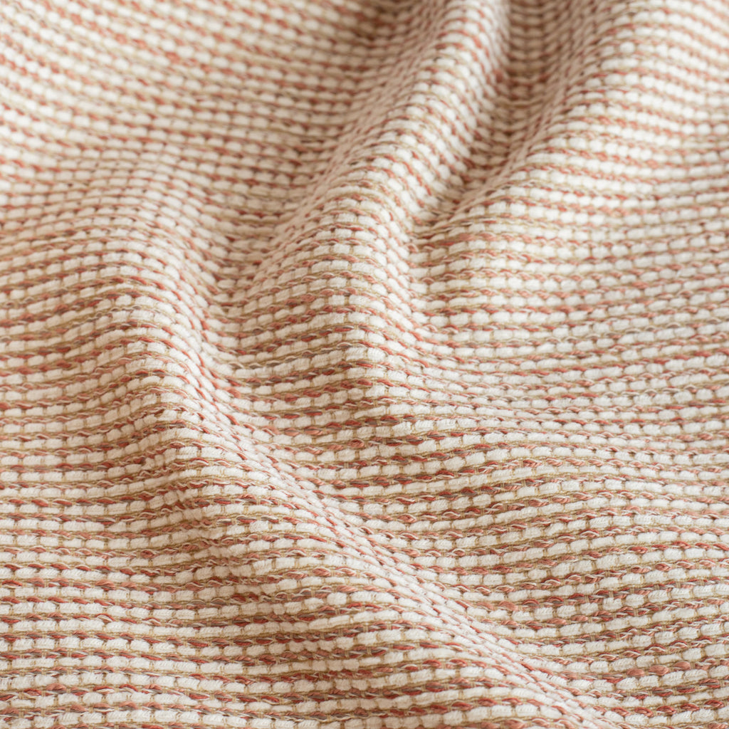 a terracotta pink and cream tweedy textured indoor outdoor upholstery fabric : close up view