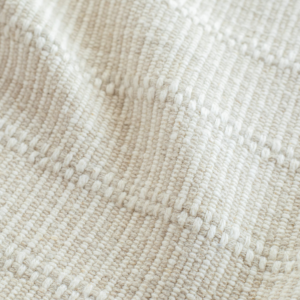 a beige and cream neutral tonal textured woven striped upholstery fabric: close up view
