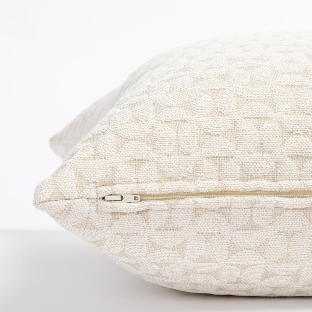 a plush white geometric quilted patterned pillow : close up zipper view