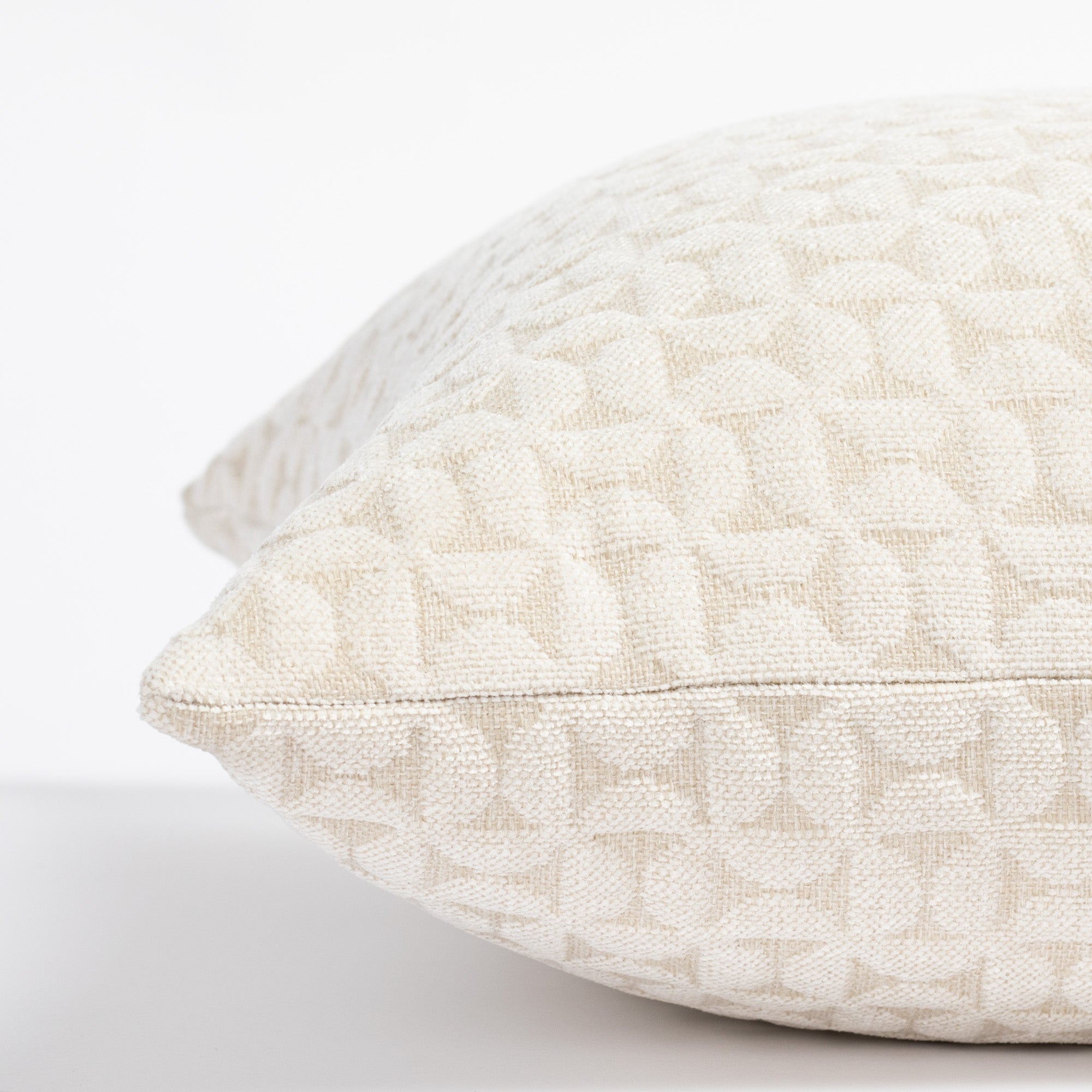 a plush white geometric quilted patterned pillow : close up side view