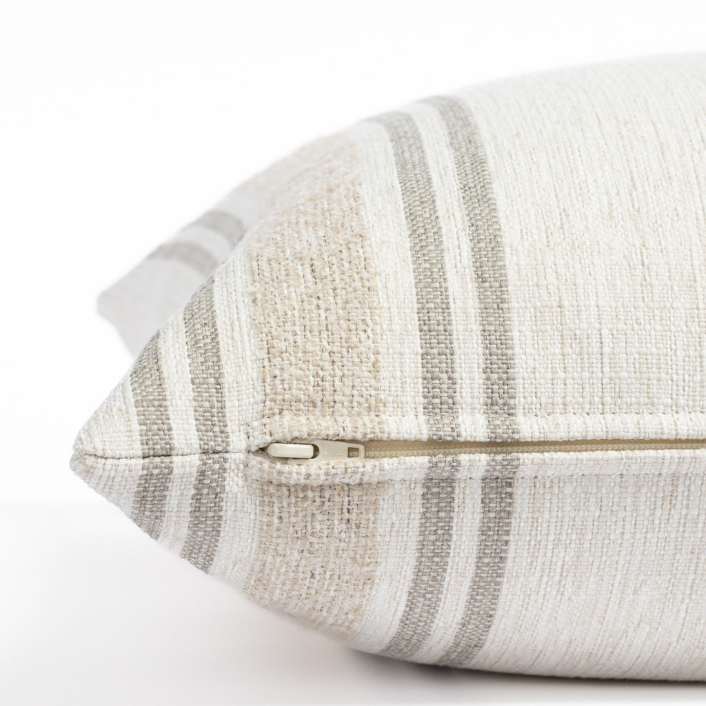 a white, cream and taupe indoor outdoor striped pillow : close up zipper view