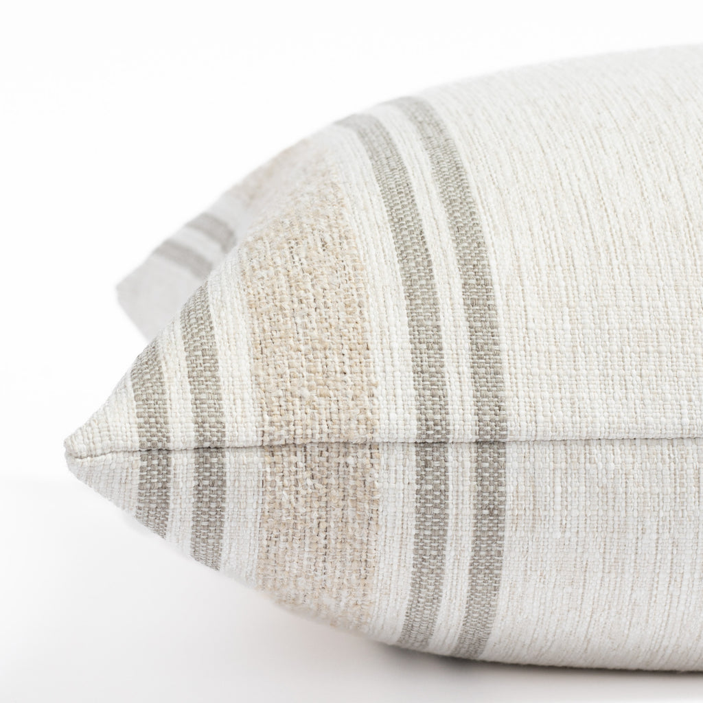a white, cream and taupe indoor outdoor striped pillow : close up side view