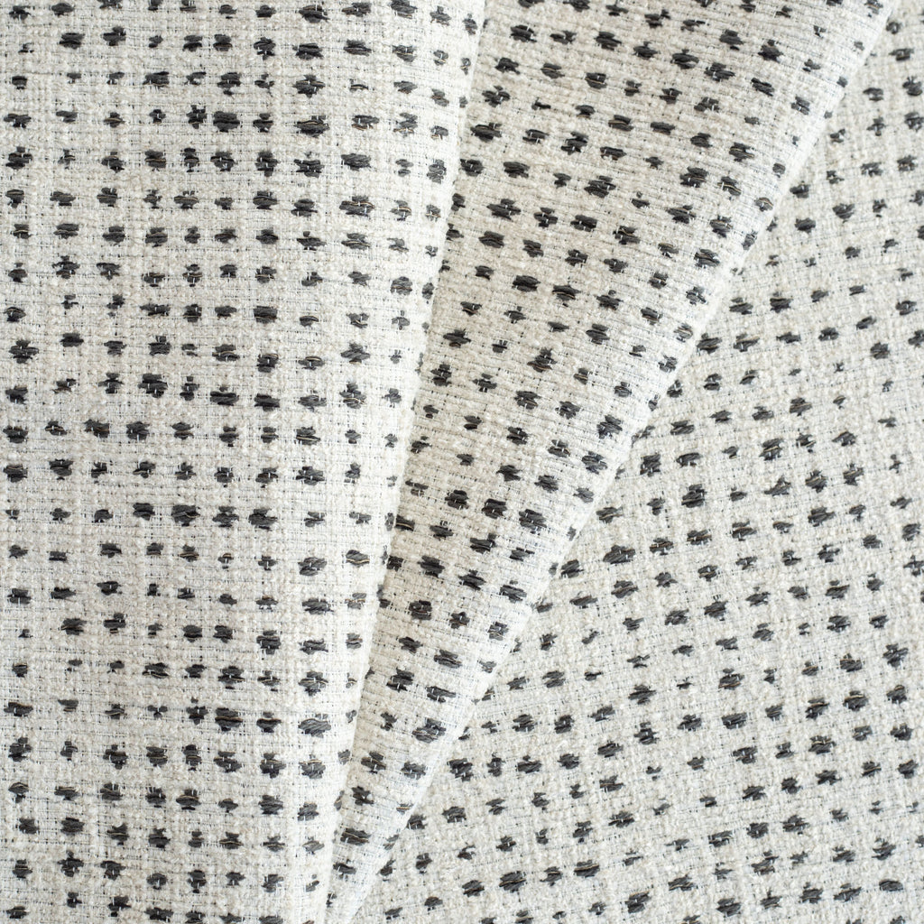 Celeste Fabric Domino, an off-whitee and black variegated polka-dot patterned textured upholstery fabric from Tonic Living