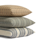 Stack of Tonic Living pillows featuring Walker Plaid, Clark Stripe, and Miller Stripe in coordinating blue, brown, and neutral tones.
